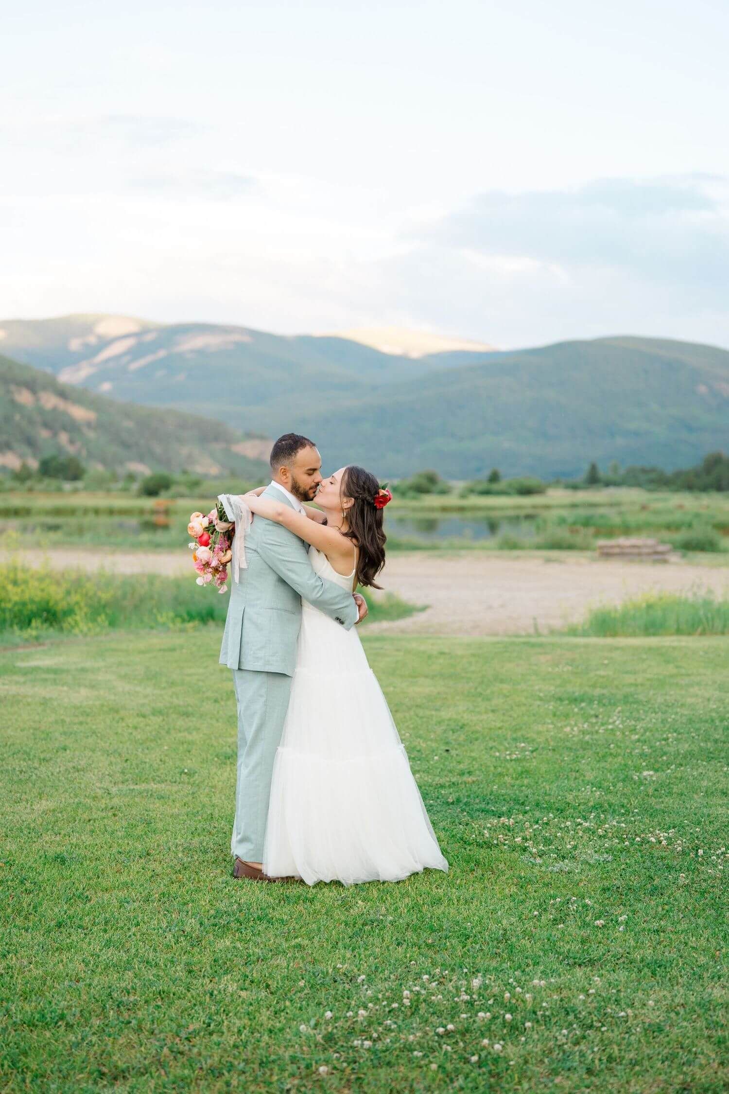 Romantic wedding couple at camp hale dancing in an open field with mountains in the background.