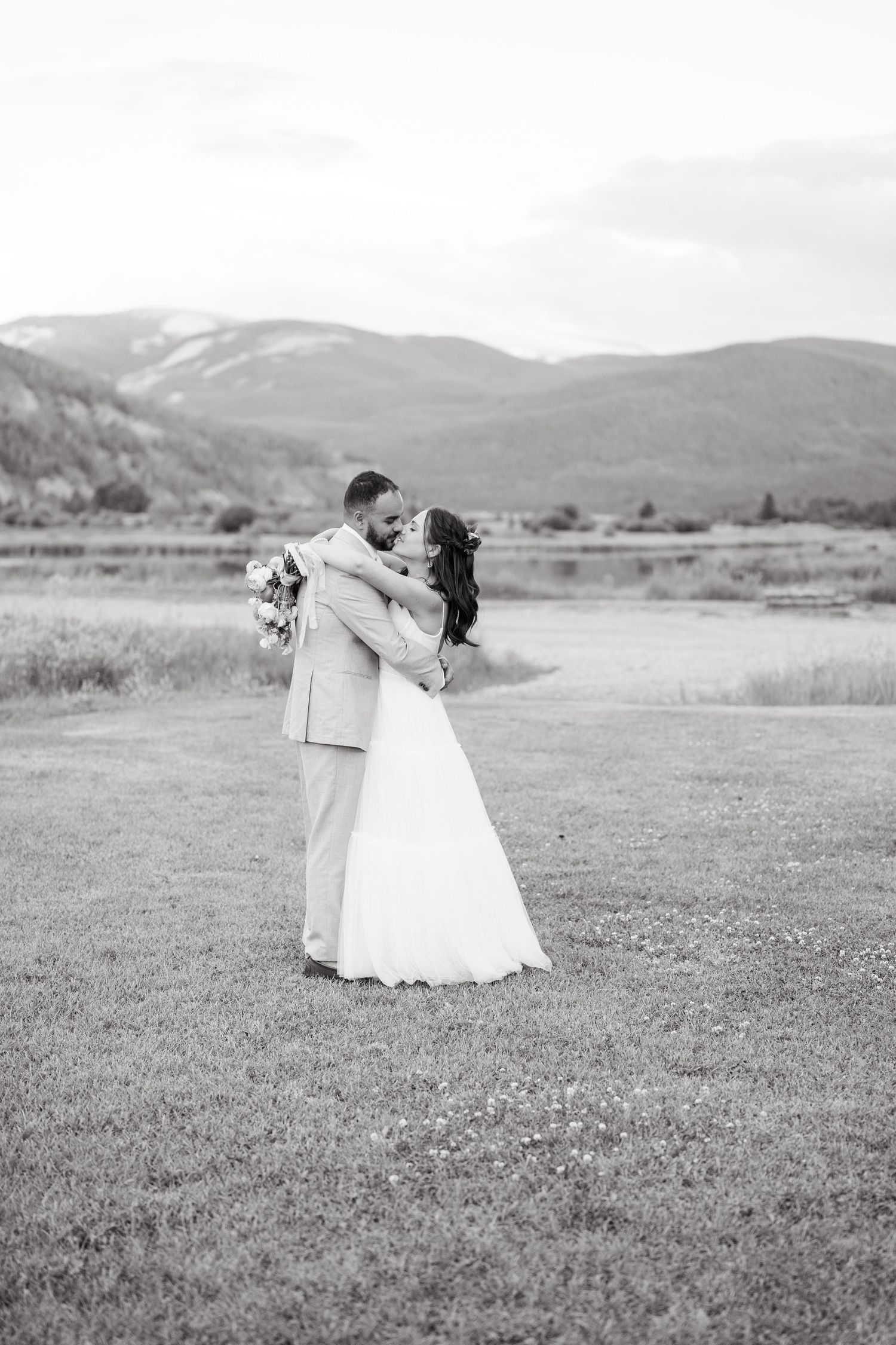 A romantic black and white wedding photo sequence showing a couple dancing in a scenic mountain meadow.