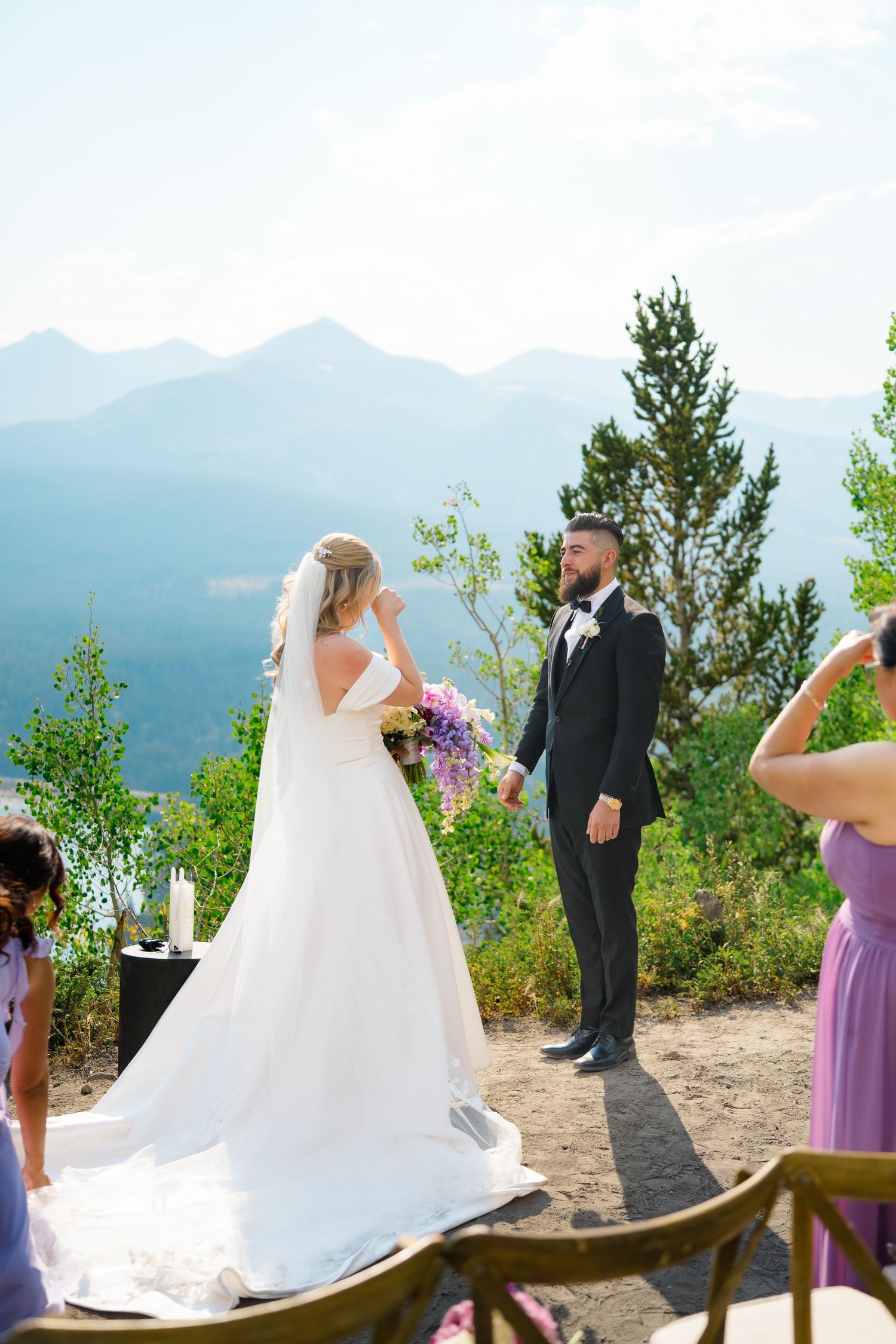 A wedding ceremony scene on a mountain overlook with attendants in purple dresses.
