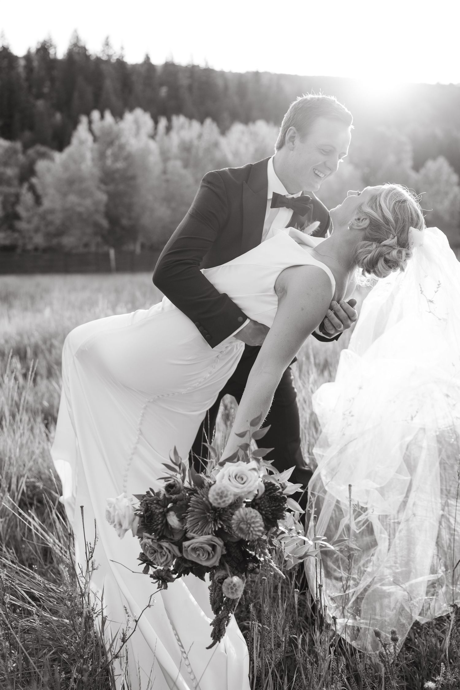 A romantic outdoor photo shoot in tall grass with flowing white dress and bouquet creating dreamy atmosphere.