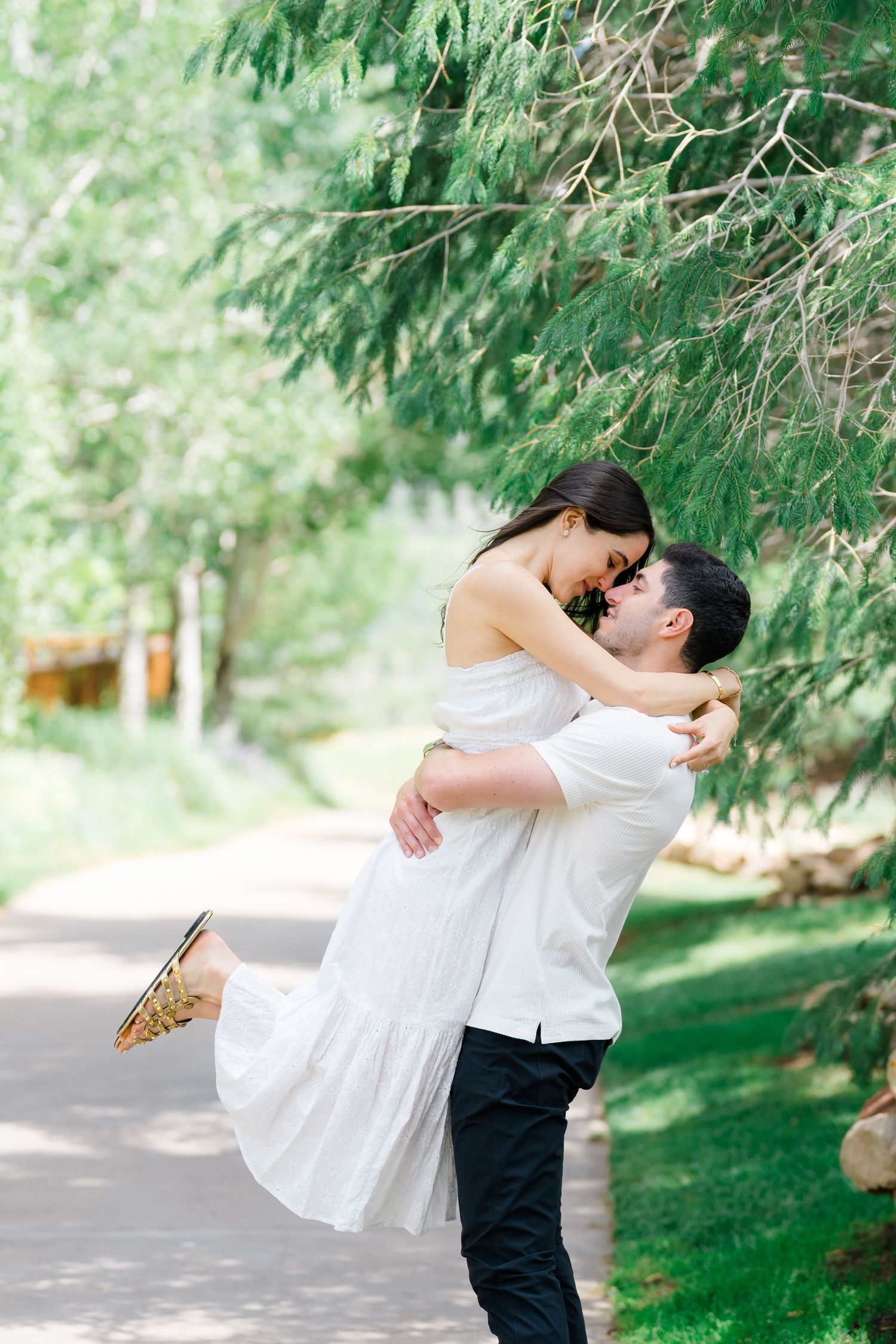 A romantic embrace captured in a series of photos against a backdrop of evergreen trees.