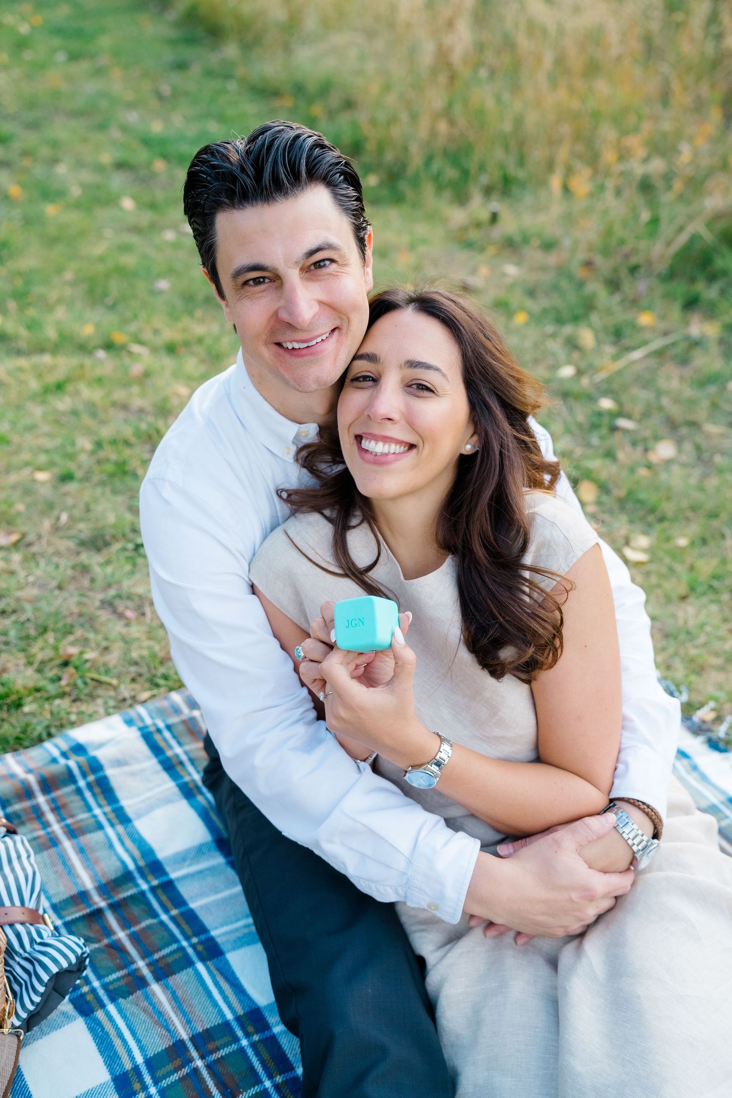 A couple sharing intimate moments on a blue plaid blanket during an outdoor picnic during vail proposal session.