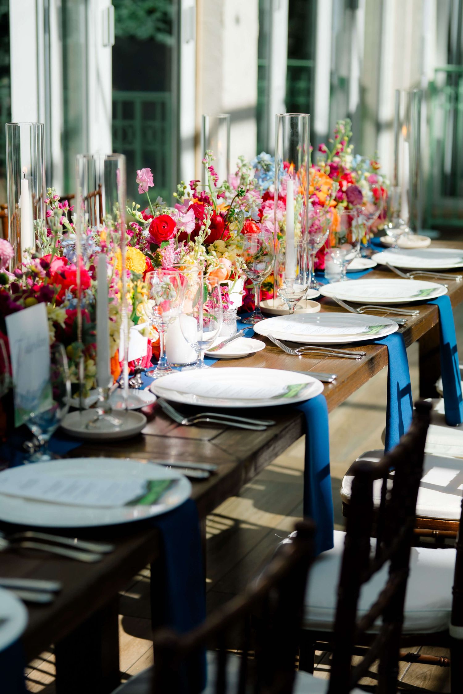 Sonnenalp Elegant Vail wedding reception table with colorful floral centerpieces, white place settings, and blue ribbon chair accents.