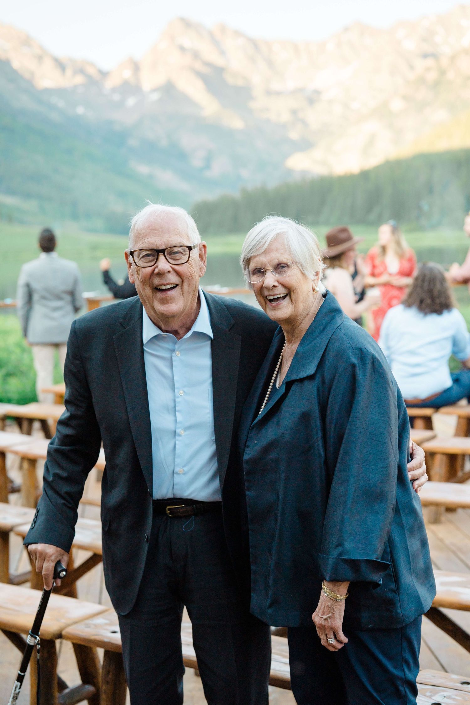 Smiling elderly couple posing outdoors at a mountain venue during a social gathering at sunset at Piney River Ranch Wedding.