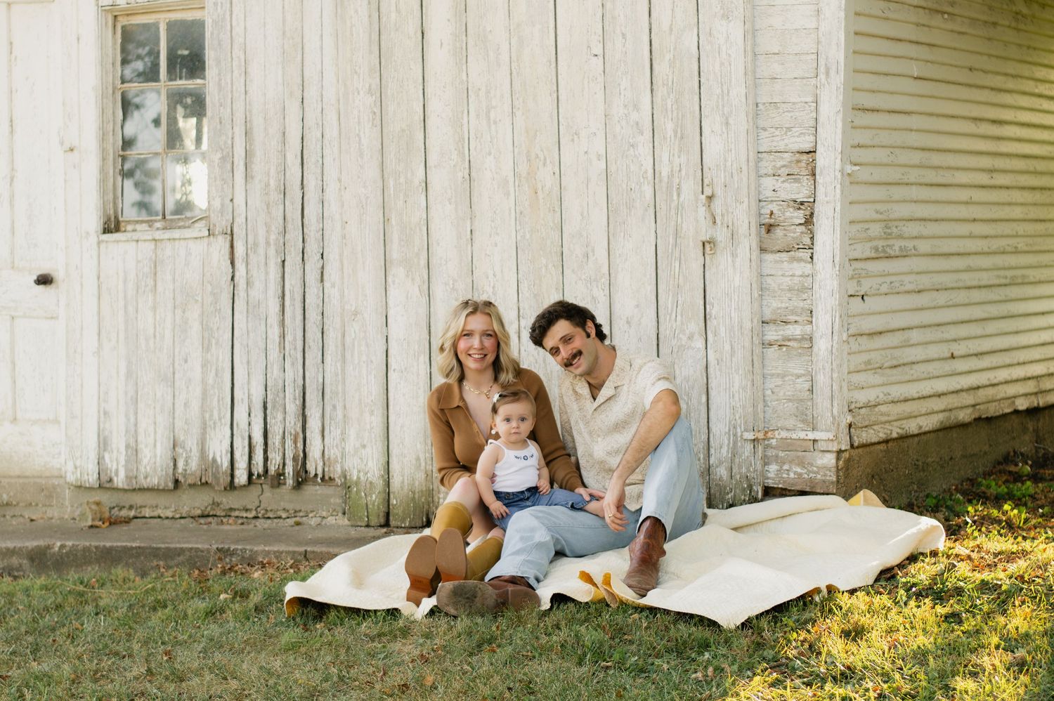 Heartwarming fall family photo outdoors — cozy sweaters, golden leaves, a playful pup, and sweet baby smiles.