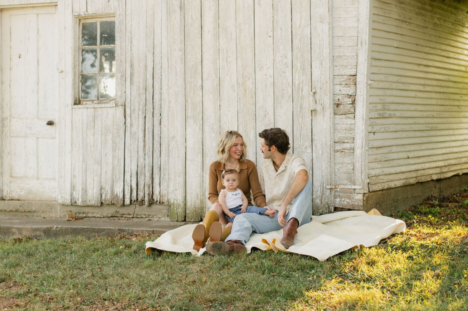 Heartwarming fall family photo outdoors — cozy sweaters, golden leaves, a playful pup, and sweet baby smiles.