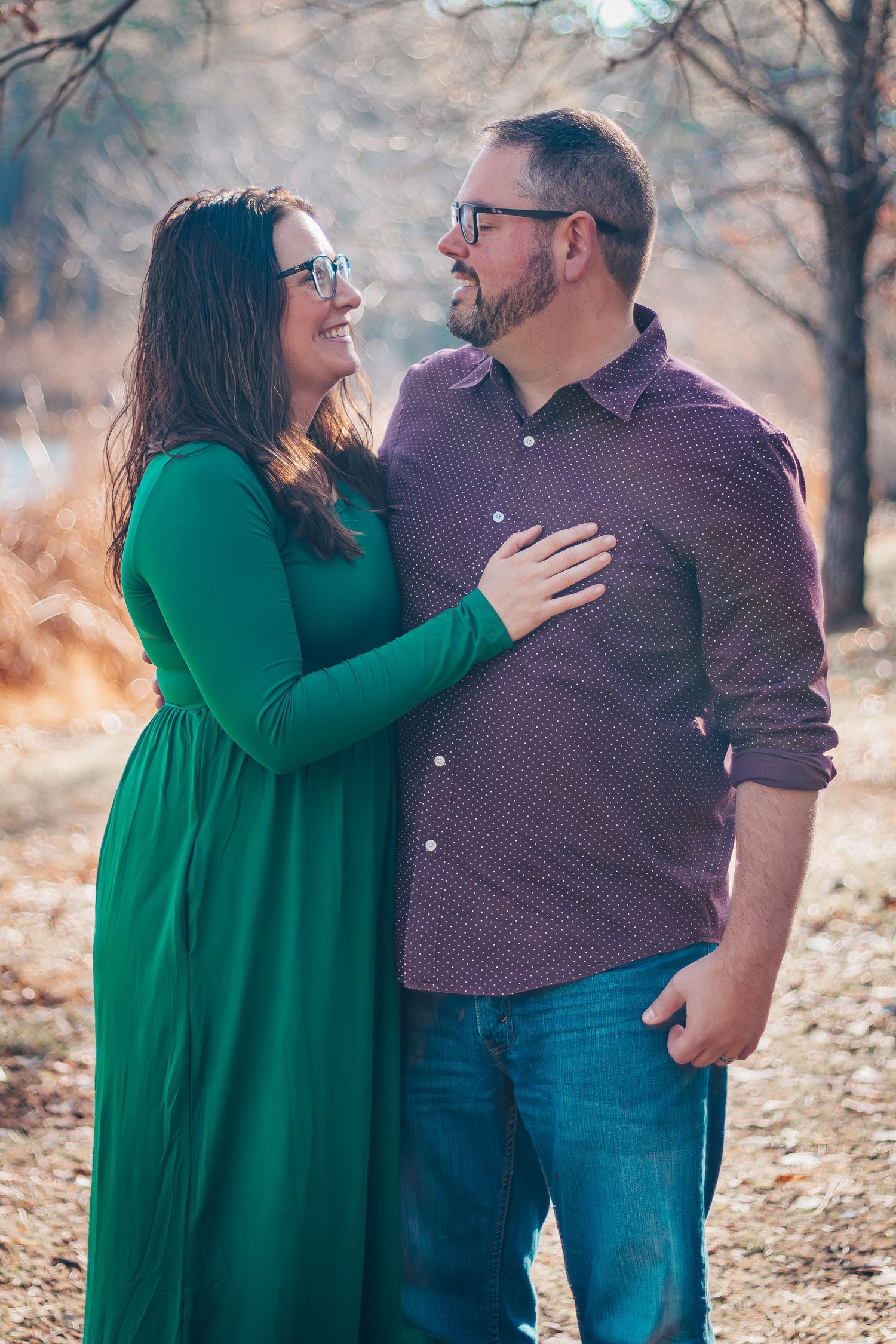A couple in casual attire sharing joyful moments together in a wooded outdoor setting during autumn.