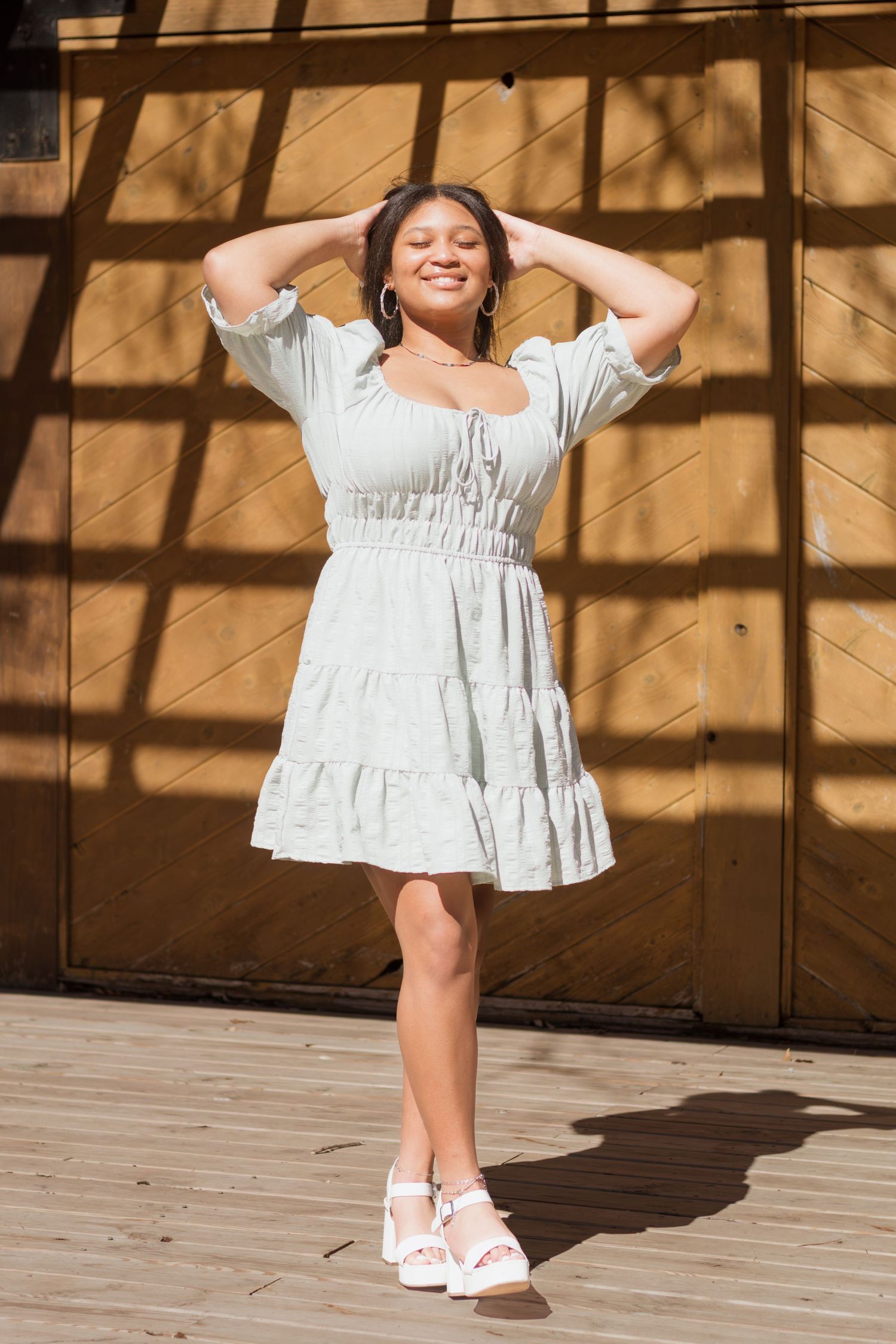 A person in a white summer dress and sneakers poses playfully in a series of photos with dramatic shadow patterns.