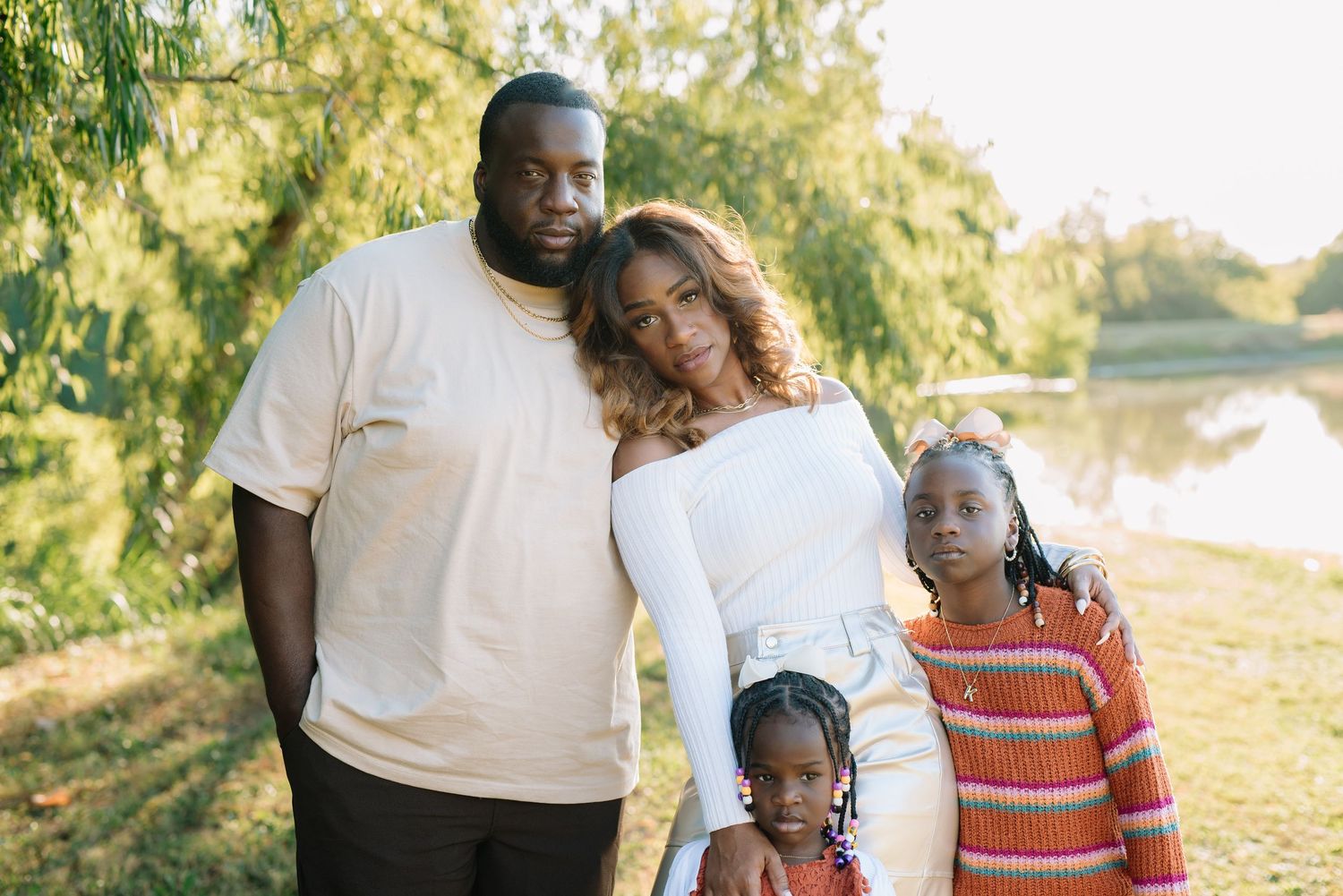 A family in coordinated outfits poses together outdoors during a golden sunset photoshoot session.