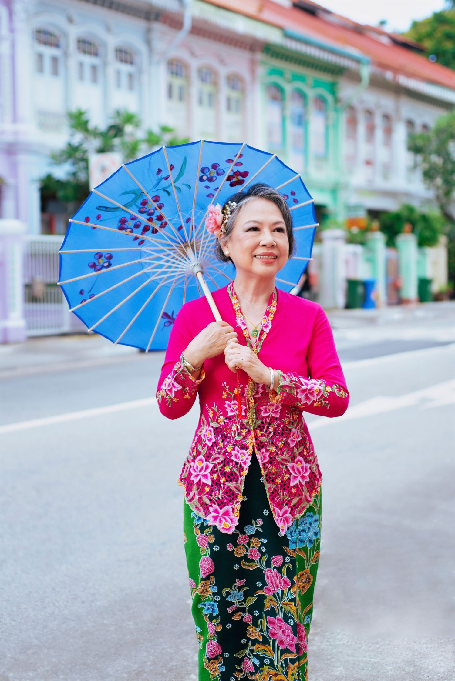 Traditional Southeast Asian fashion displayed on a street with colorful parasol and decorative floral patterns.