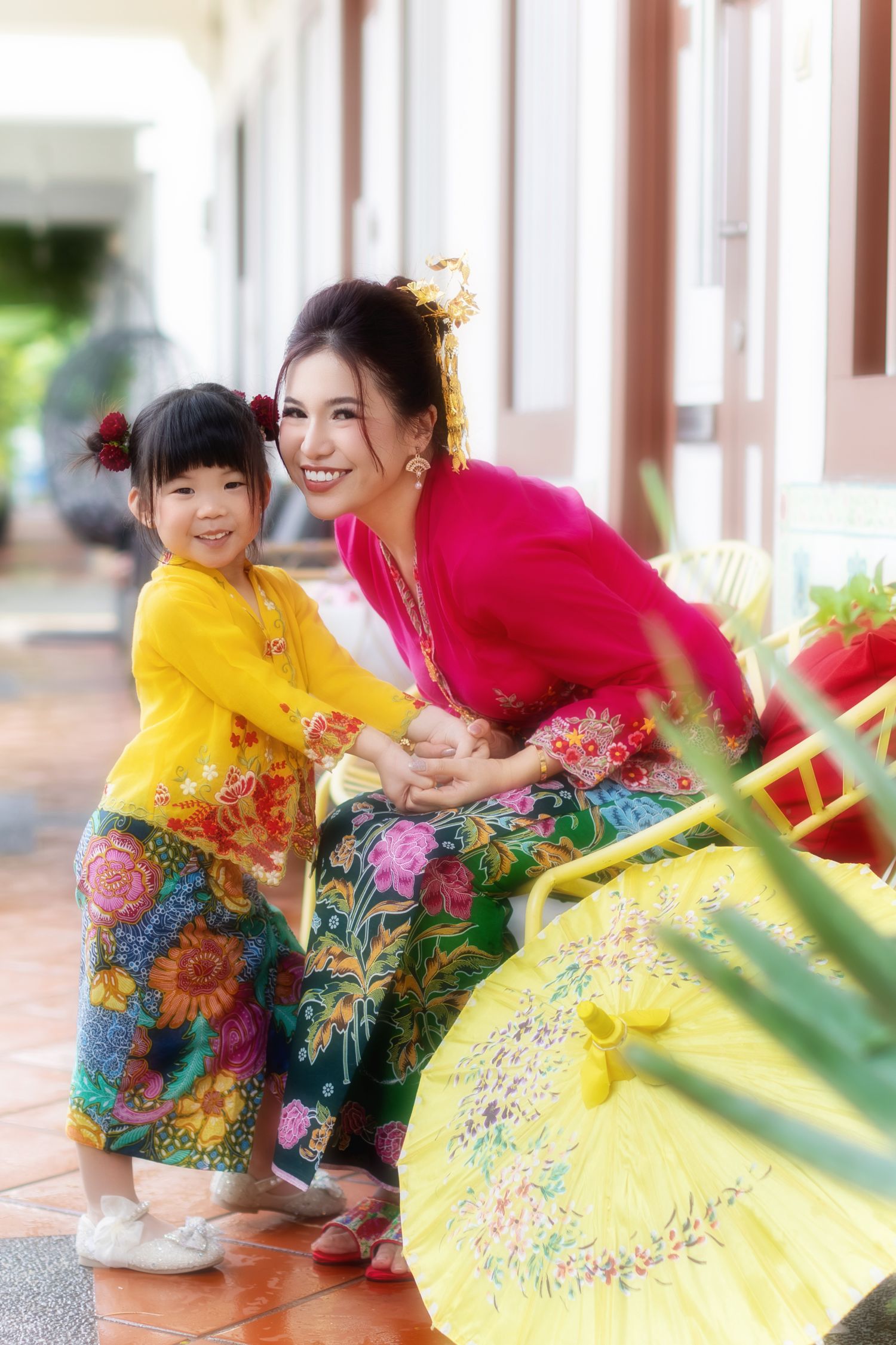 Image of a Nyonya mother and daughter in Kebaya and batik sarong, sitting on porch chair at a Peranakan house in Joo Chiat.
