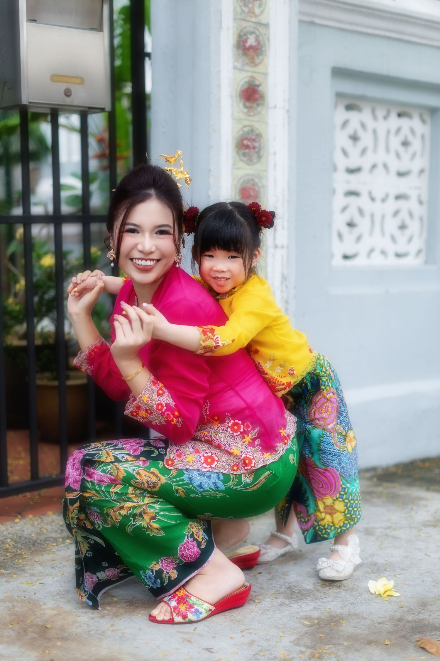 Picture of a Nyonya mummy and daughter in pink and yellow kebaya, posing at a Peranakan house at Joo Chiat, at Koon Seng road.