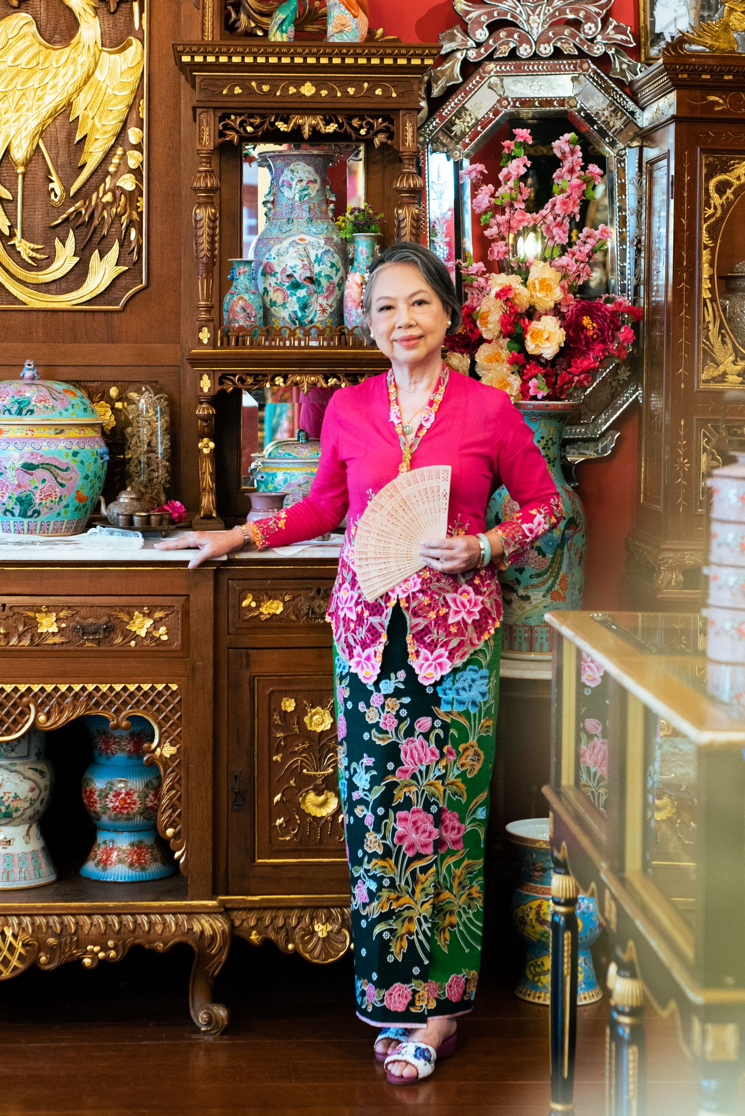 Traditional Peranakan decor and design displayed in a shop with ornate wooden furniture and colorful antique vases.