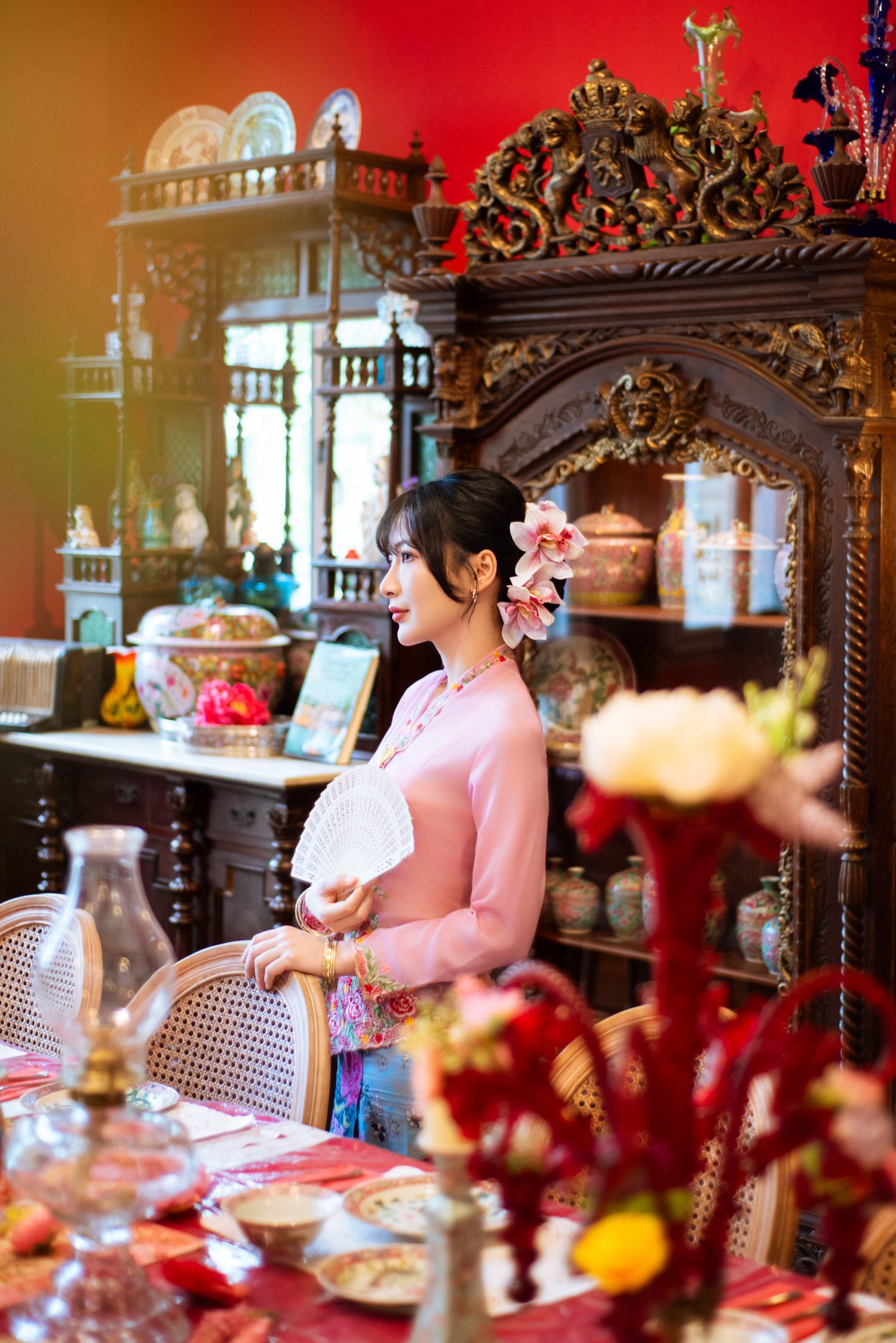 Ornate vintage dining room with elaborate wooden furniture displays and pink elements in an elegant tea party setting.