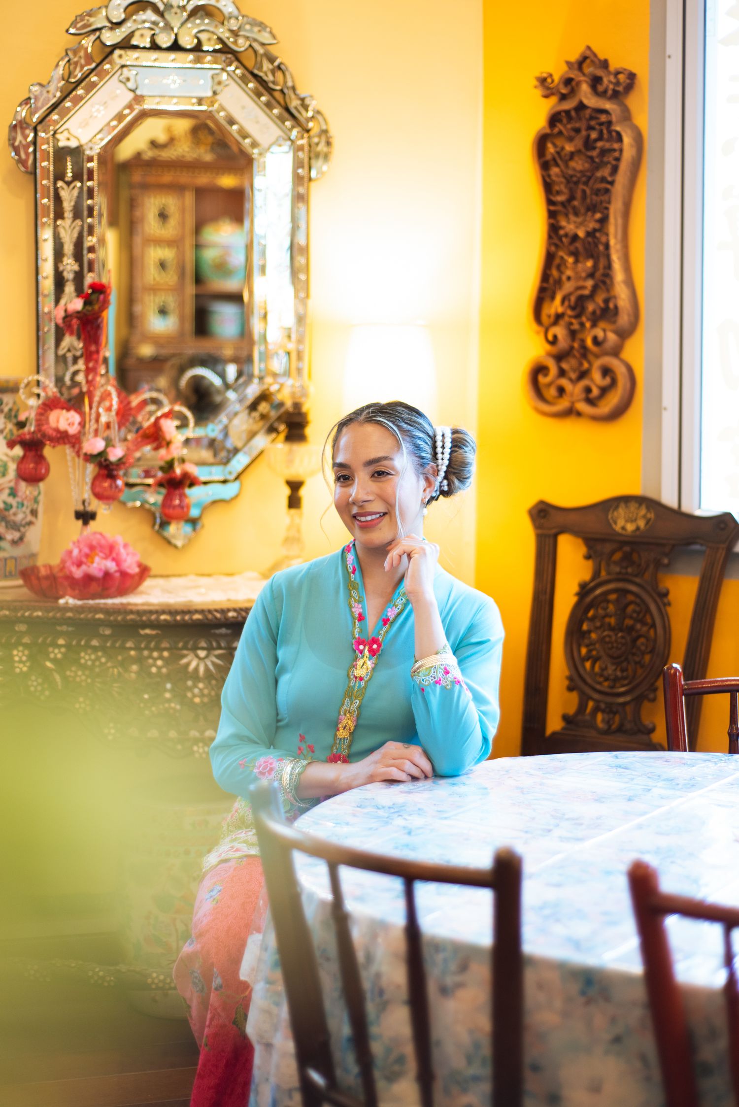 Interior scene with ornate vintage mirror, yellow walls and decorative furniture in warm natural lighting.