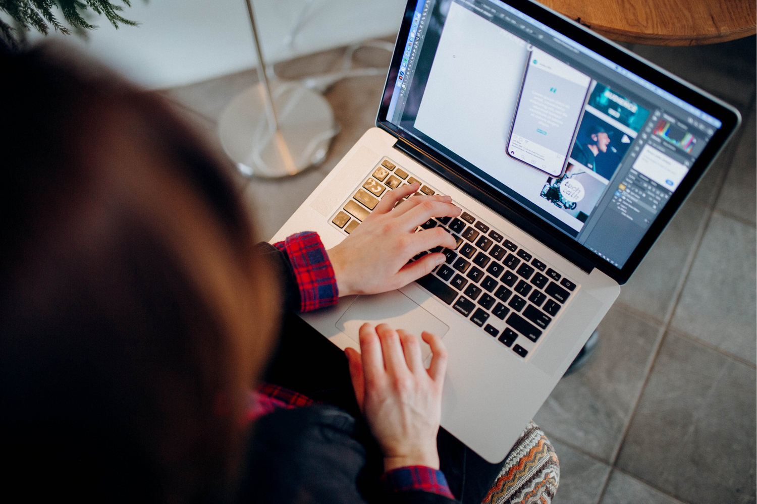 Employee working at a laptop computer on a desk surface, doing image photoshop or photo editing or picture retouch
