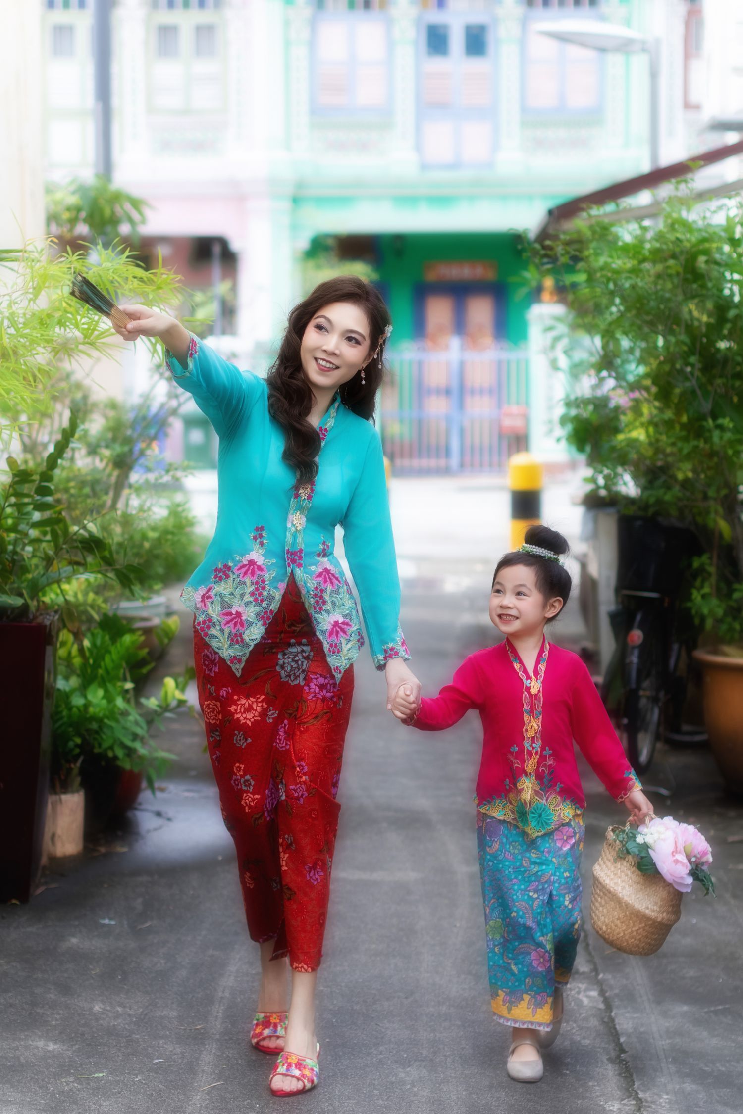 Photoshoot of a Mother and daughter in traditional Nyonya Kebaya walking together in front of iconic Peranakan houses.