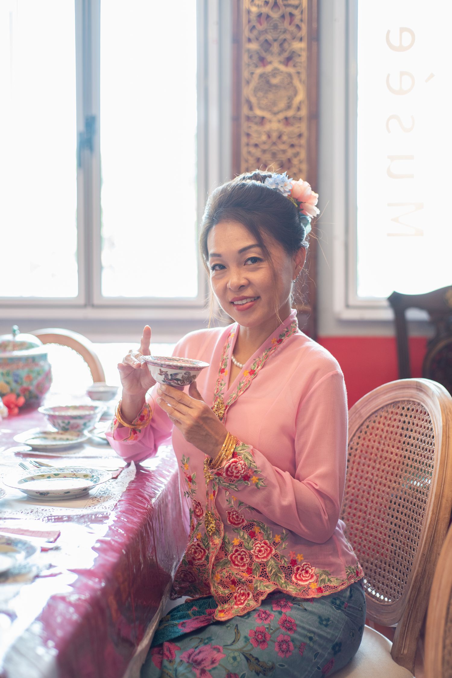 Three side-by-side photos of a person wearing a pink sweater and floral dress sitting at an elegant dining table.