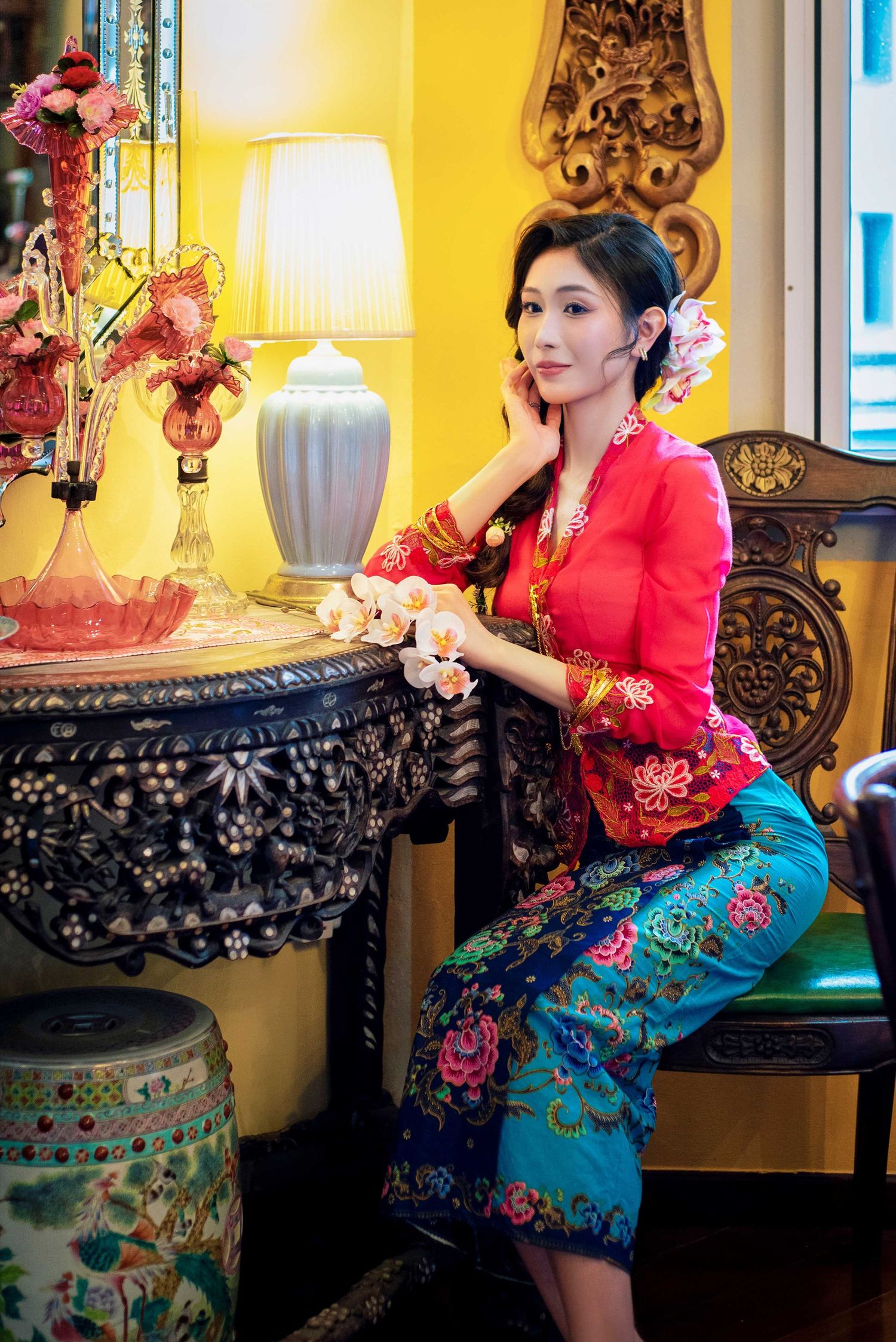 Elegant Nyonya fashion photoshoot in a heritage setting with ornate furniture and yellow walls.