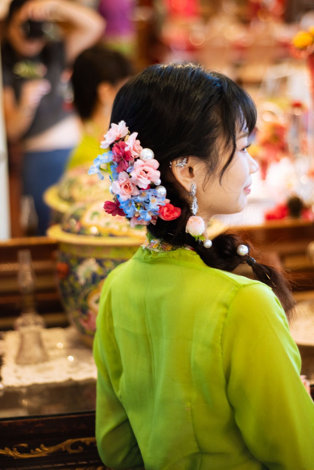 A series of photos showing someone in a bright lime green traditional dress with pink and blue floral hair accessories.