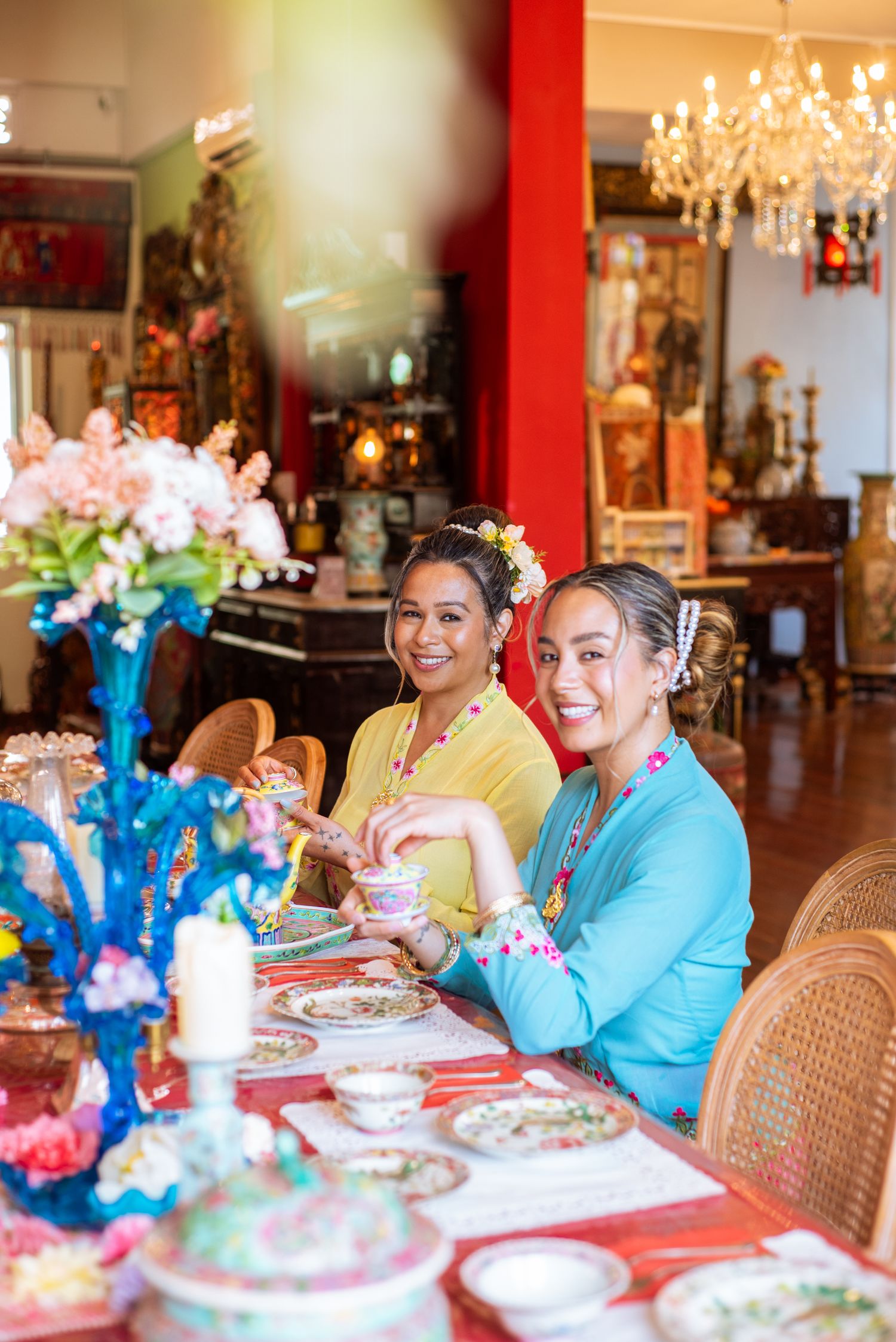 A group gathers at an elegant dining room table with crystal chandeliers and floral arrangements for a special celebration.