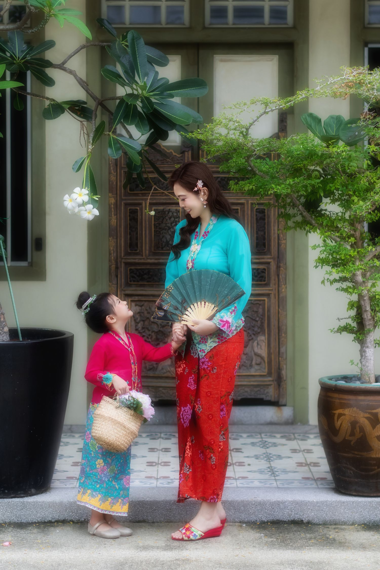 Photoshoot of mother and daughter in traditional Nyonya Kebaya posing in front of a Peranakan house.