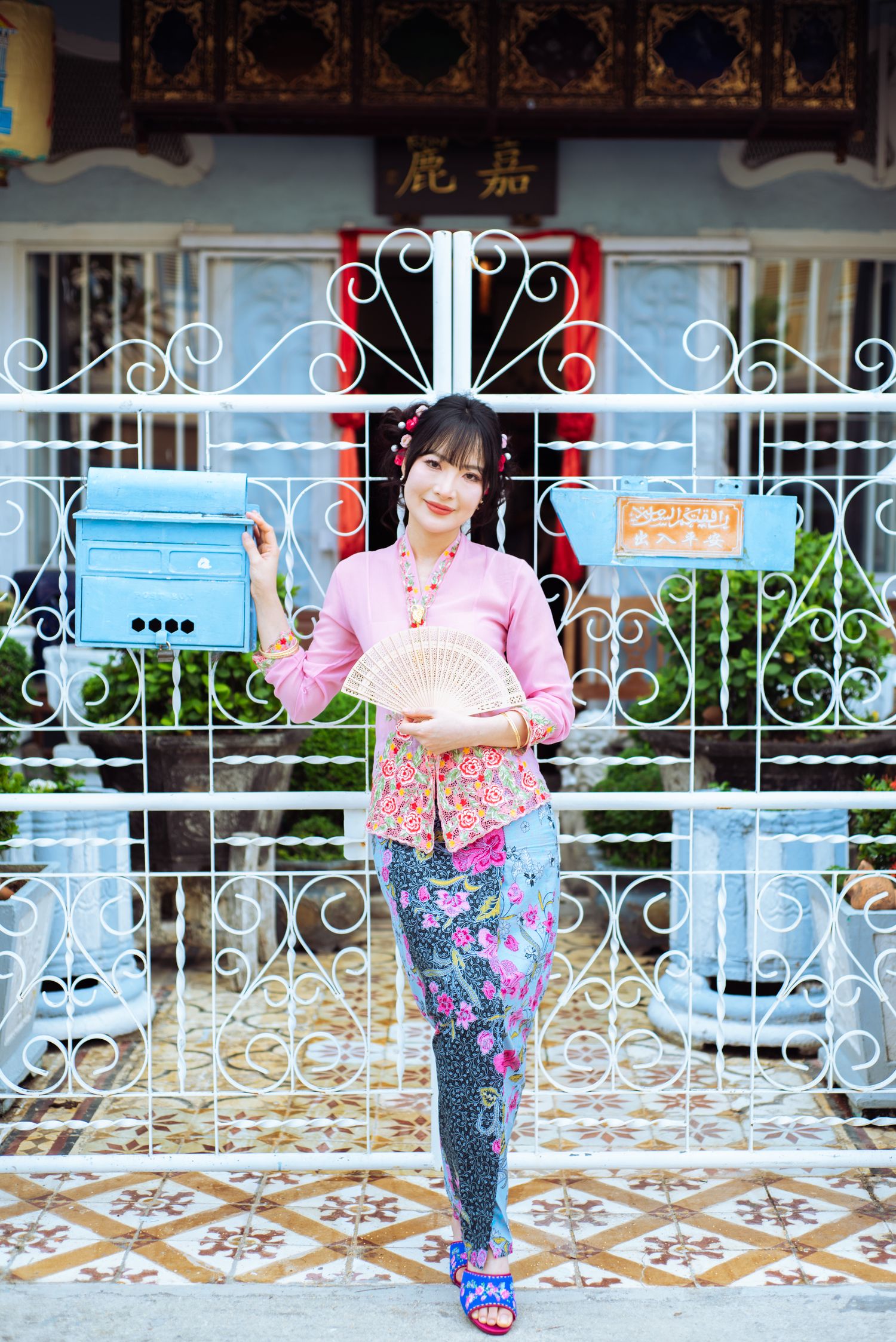Woman in colorful workout attire poses in front of ornate white wrought iron gate and tiled floor.