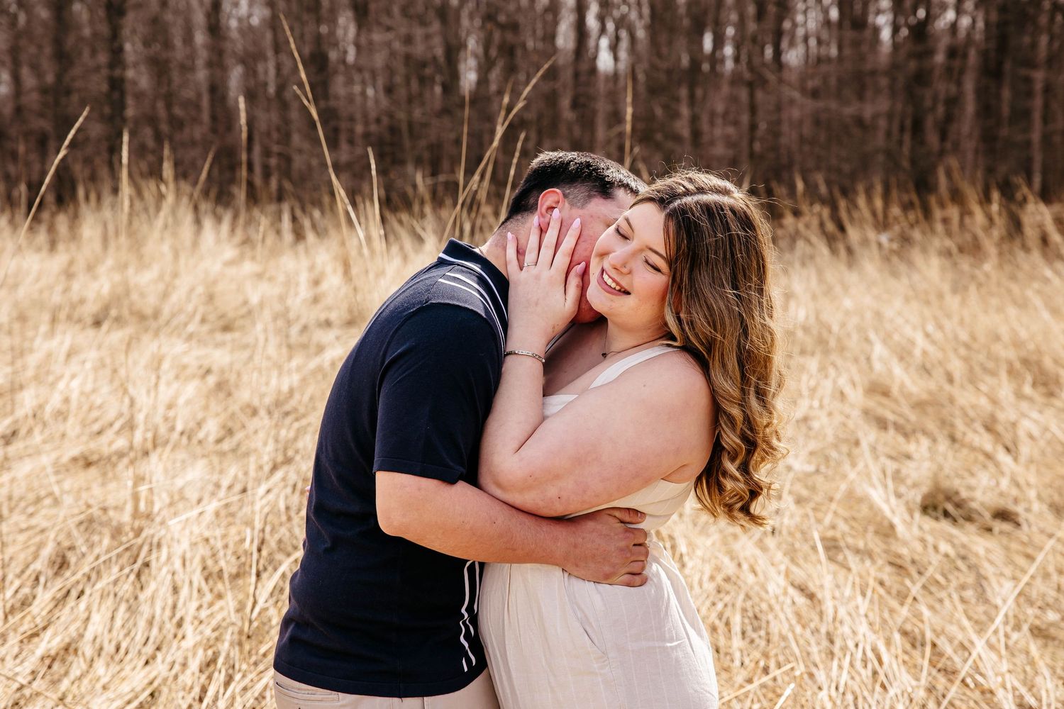 A romantic outdoor photo session in a golden autumn field with soft sunlight filtering through tall grass.