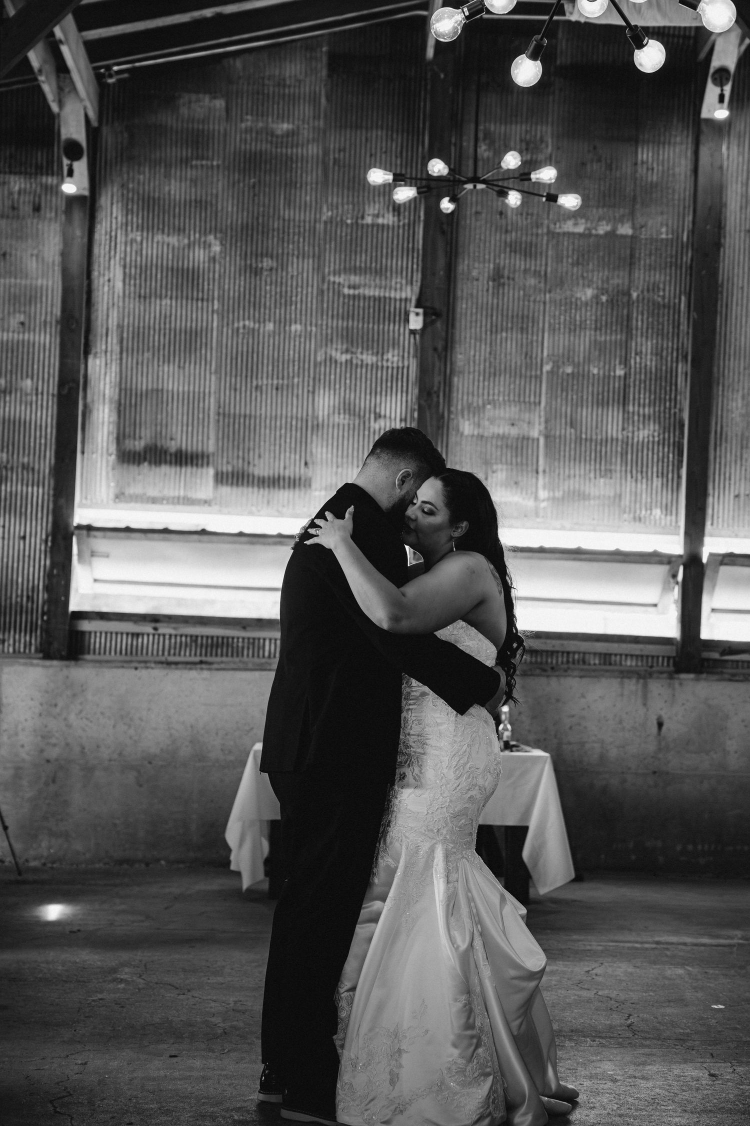A newlywed couple shares a romantic dance sequence across multiple frames in a dimly lit industrial space.