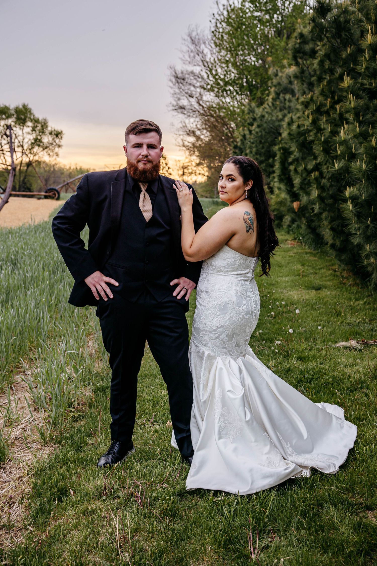 A couple poses outdoors in a grassy field with trees, showing a series of fun and playful wedding photo moments.