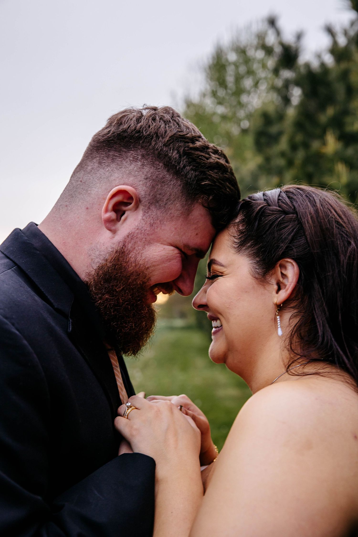 Close up of loving couple sharing intimate moment together outdoors, touching foreheads and clasping hands.