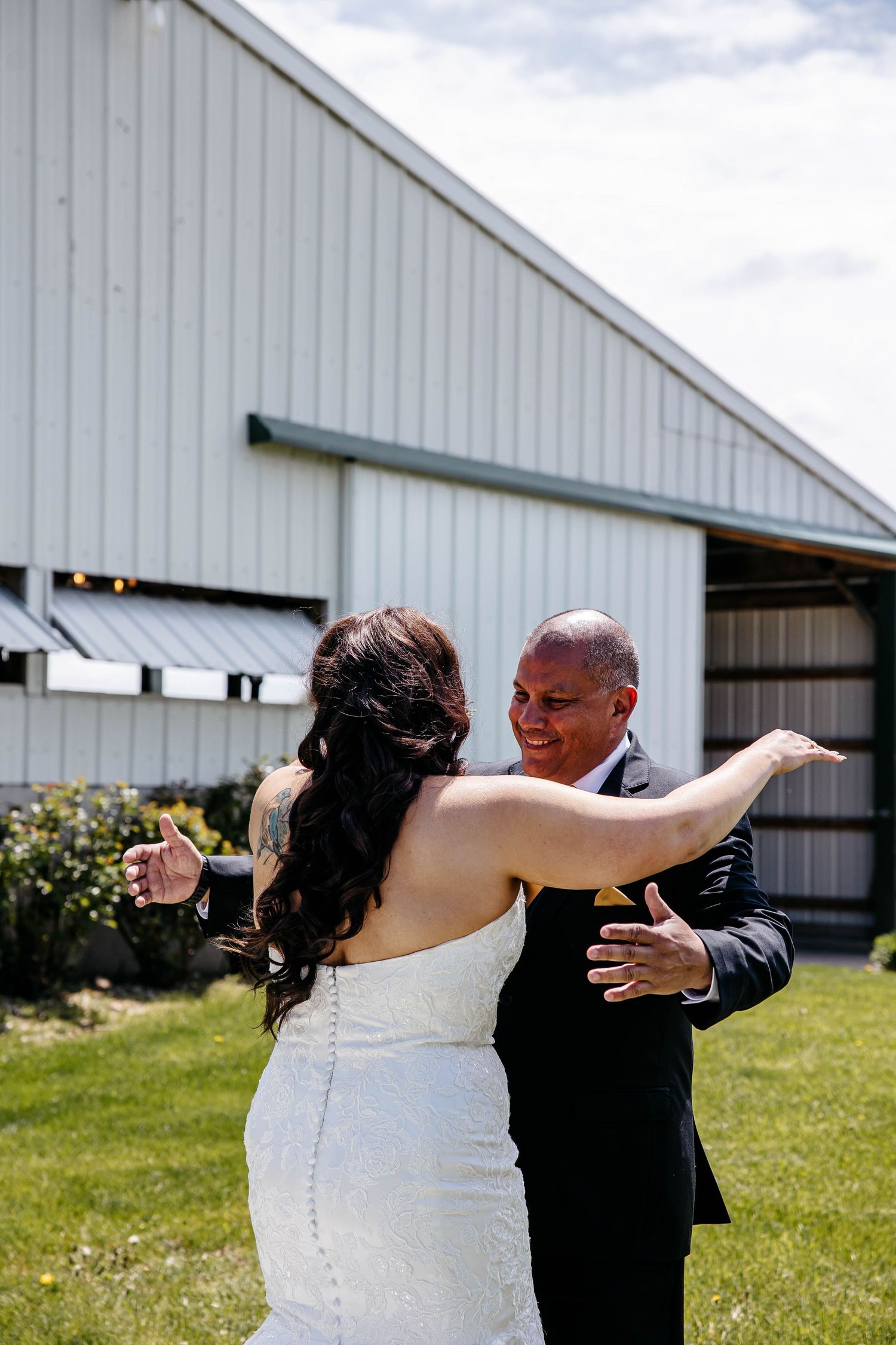 A couple shares a special first look moment outside a white barn on their wedding day.