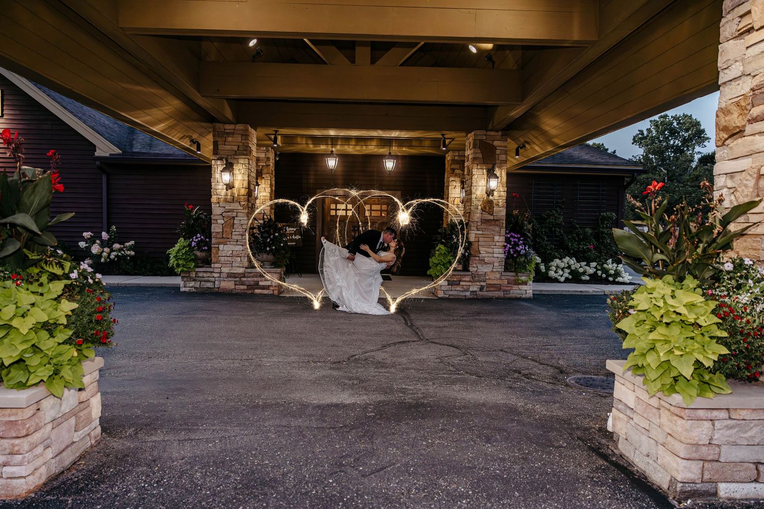 A covered porch walkway extends along the exterior of a stone building with hanging planters and lighting fixtures.