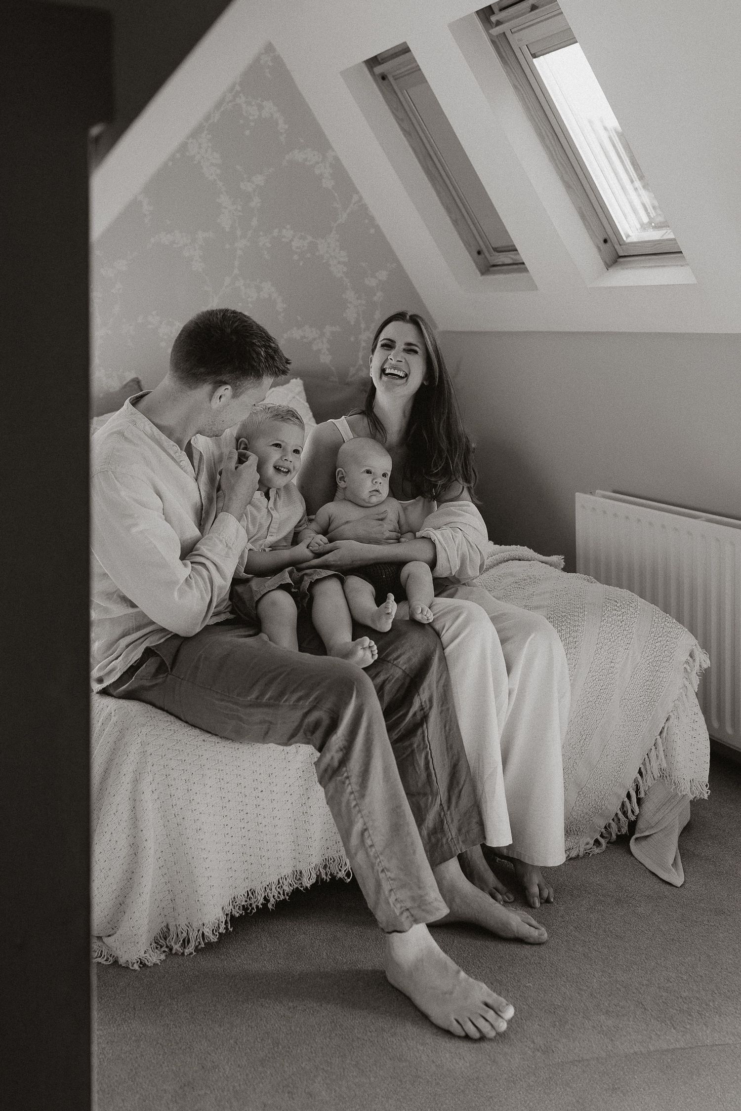 A series of black and white photographs showing intimate family moments of playful interaction on a bed.