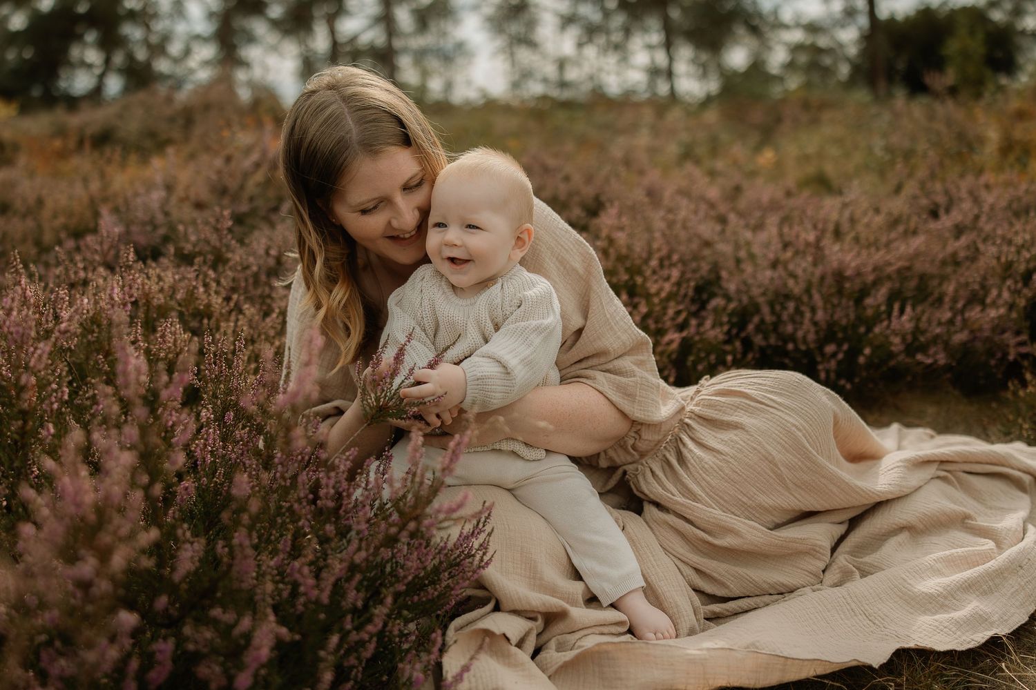 A tender moment shared between parent and child sitting among blooming purple heather flowers at sunset.