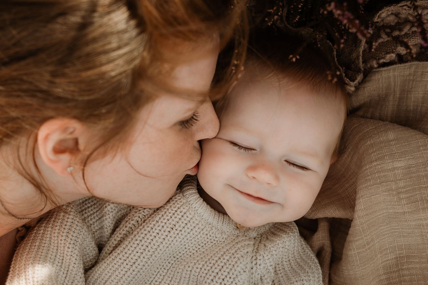 A tender moment of affection between parent and baby in cozy knit sweaters.