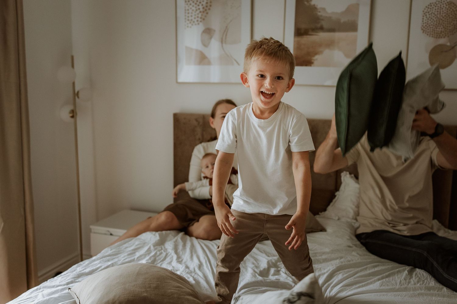 A series of connected photos showing a child jumping on a white bed in a bright, sunlit bedroom.