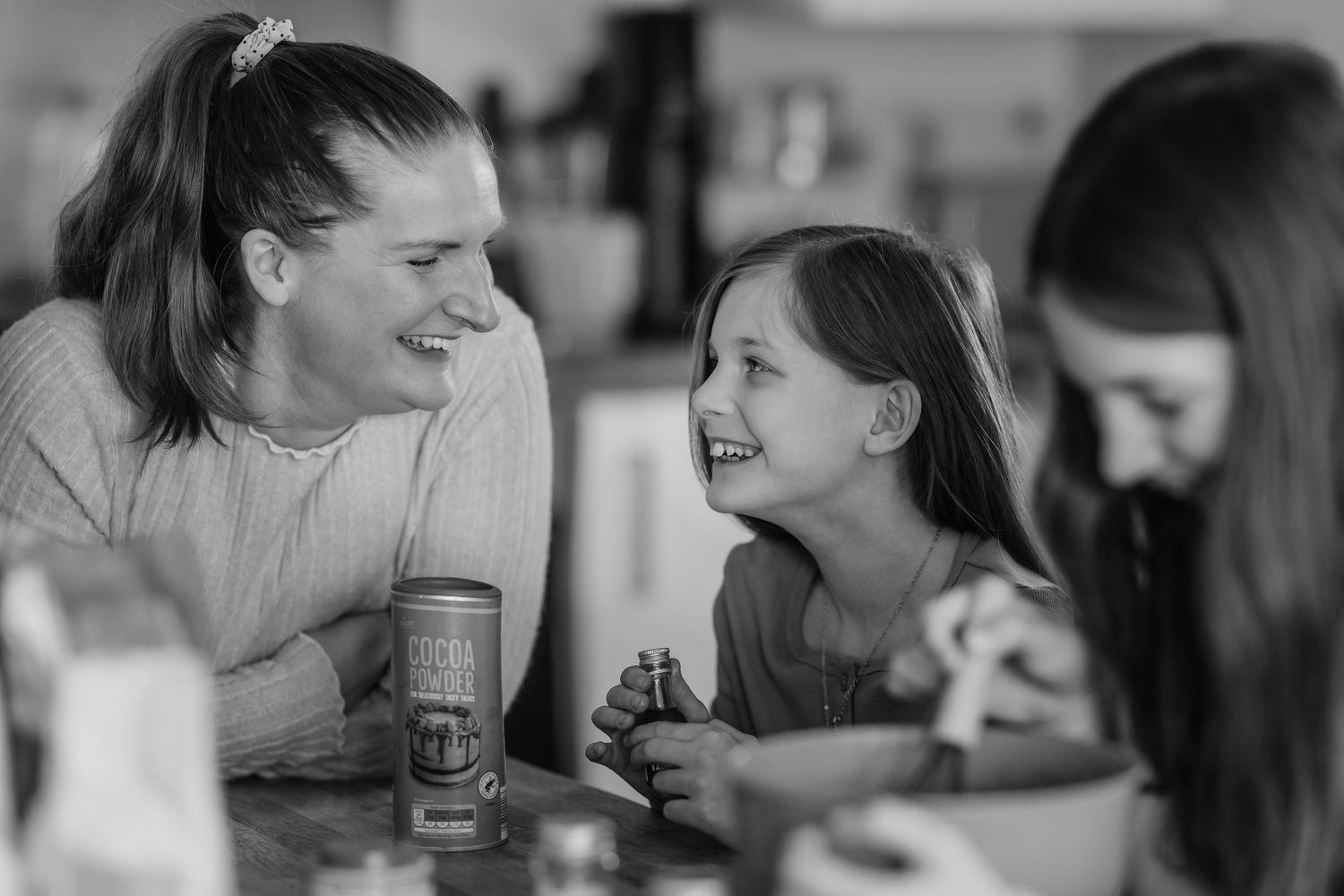 Black and white candid photo of people laughing together and enjoying a social gathering.