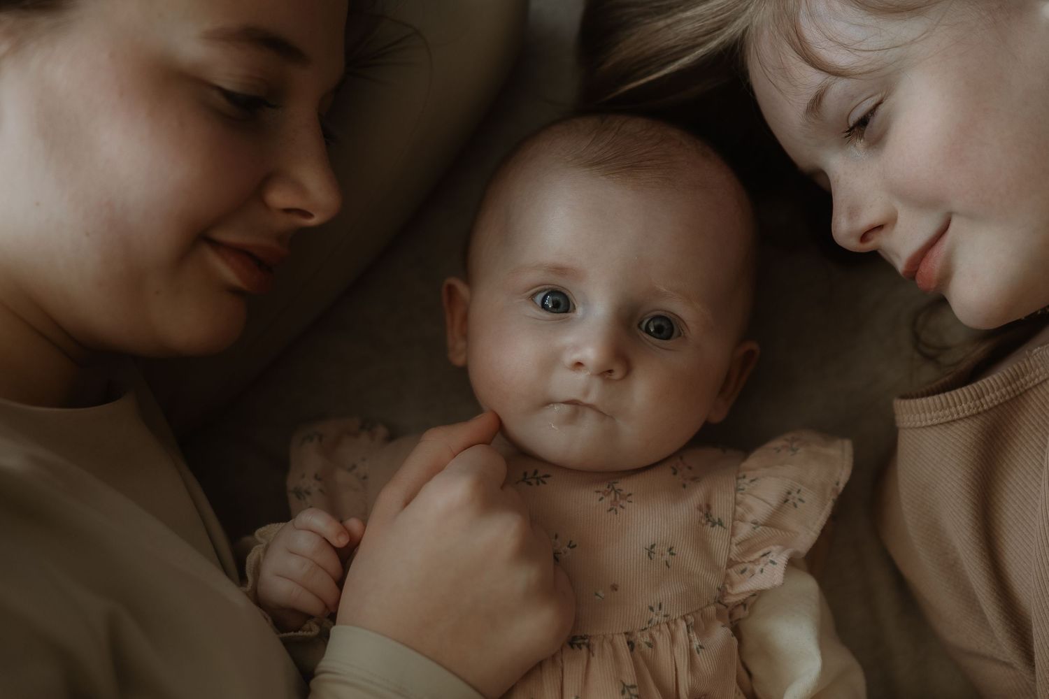 A tender moment between parent and baby in soft sepia tones showing love and connection.