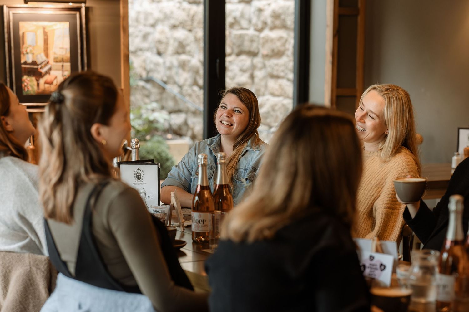 People gathered at a restaurant enjoying drinks and conversation in a warm, inviting atmosphere.