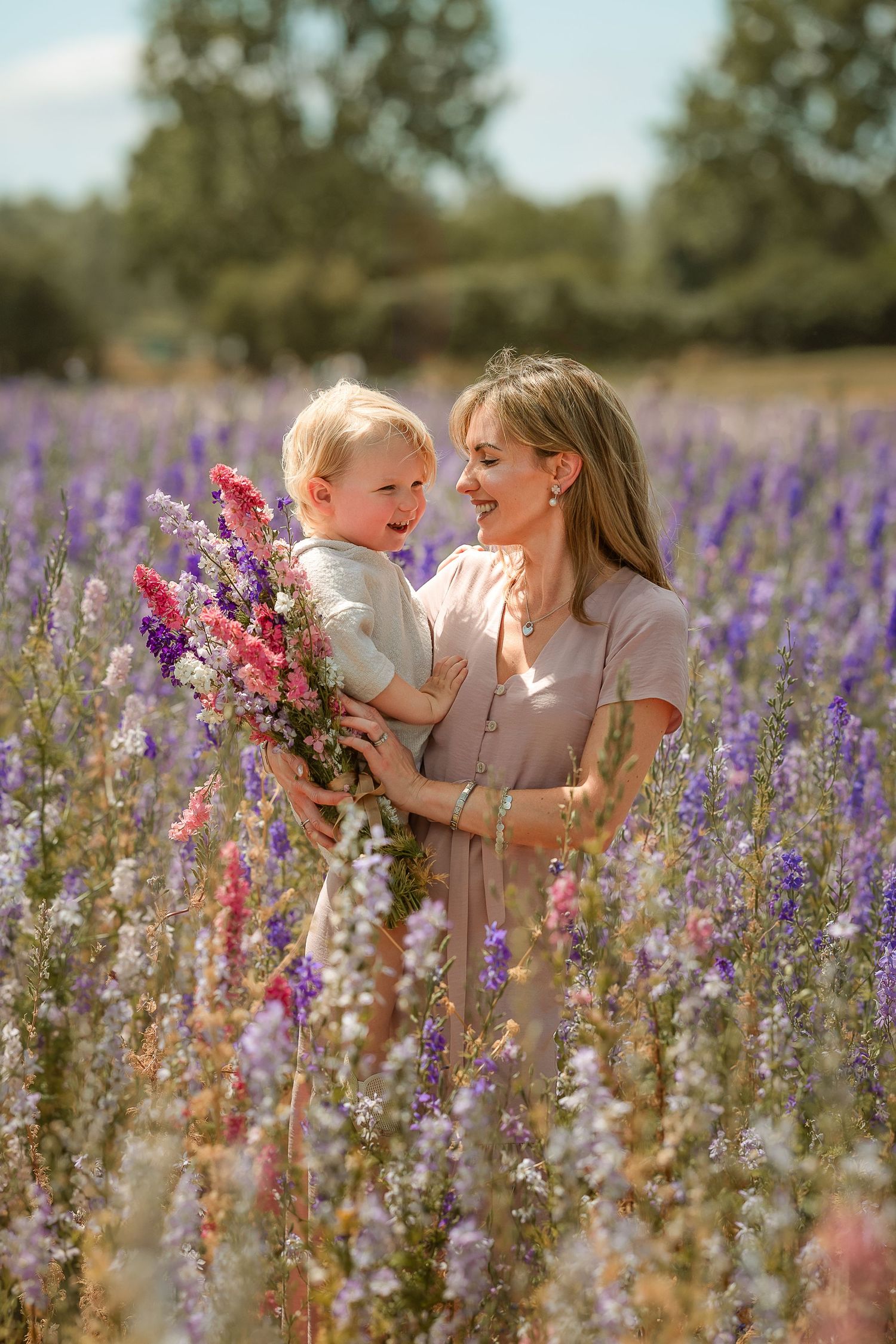 A joyful family moment captured in a field of vibrant purple and pink wildflowers on a sunny summer day.