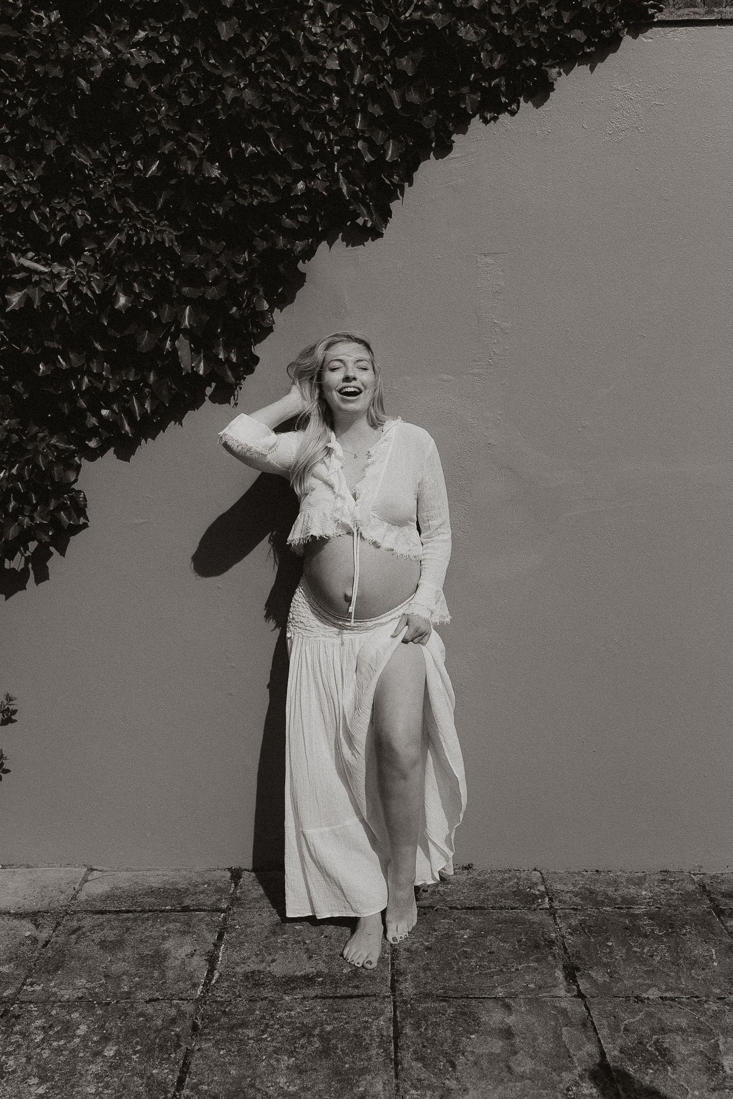 A series of black and white photographs showing a person in white clothing posing expressively against a wall.