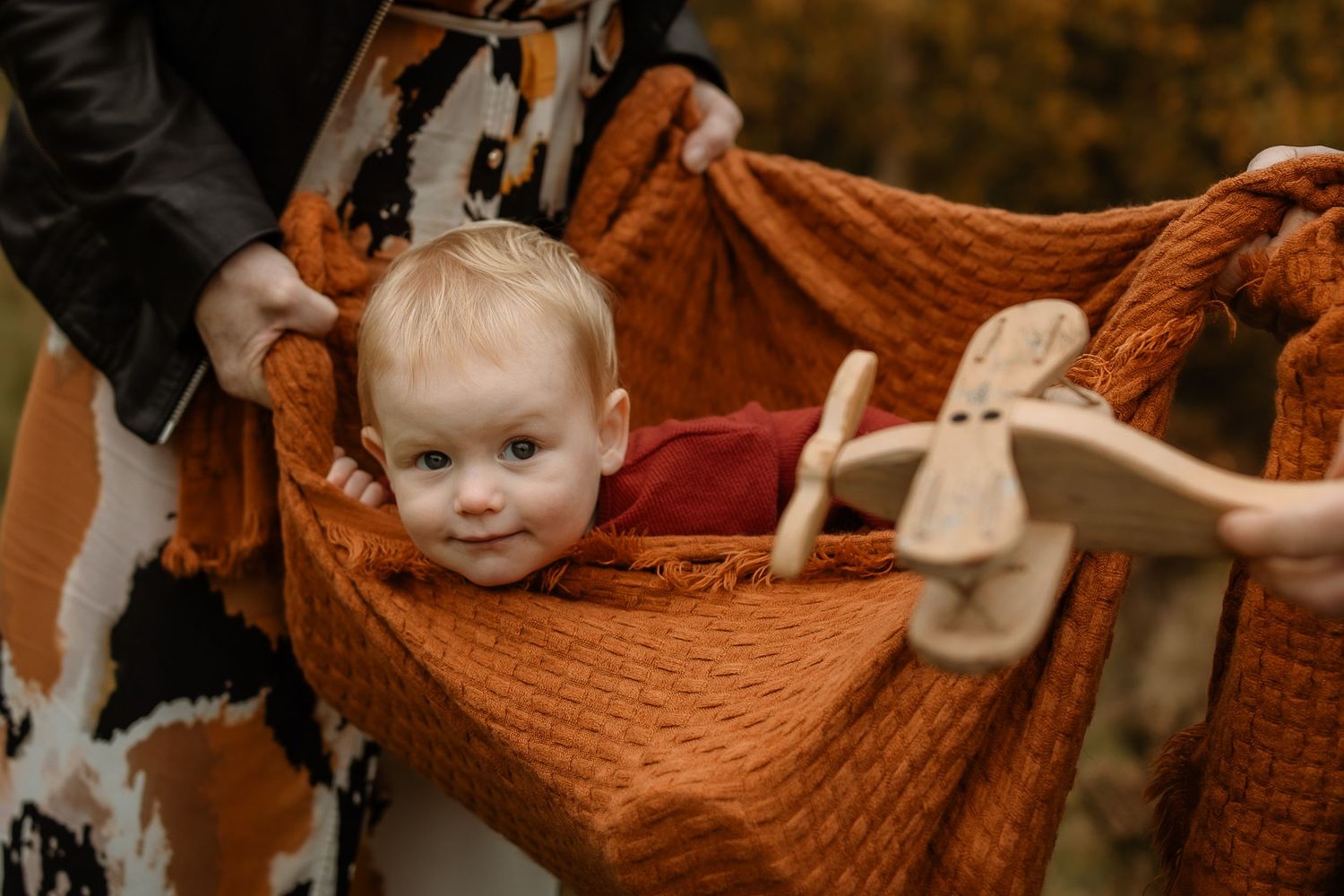 A series of warm-toned photos showing a baby in various poses with orange and brown autumn-themed decorations.