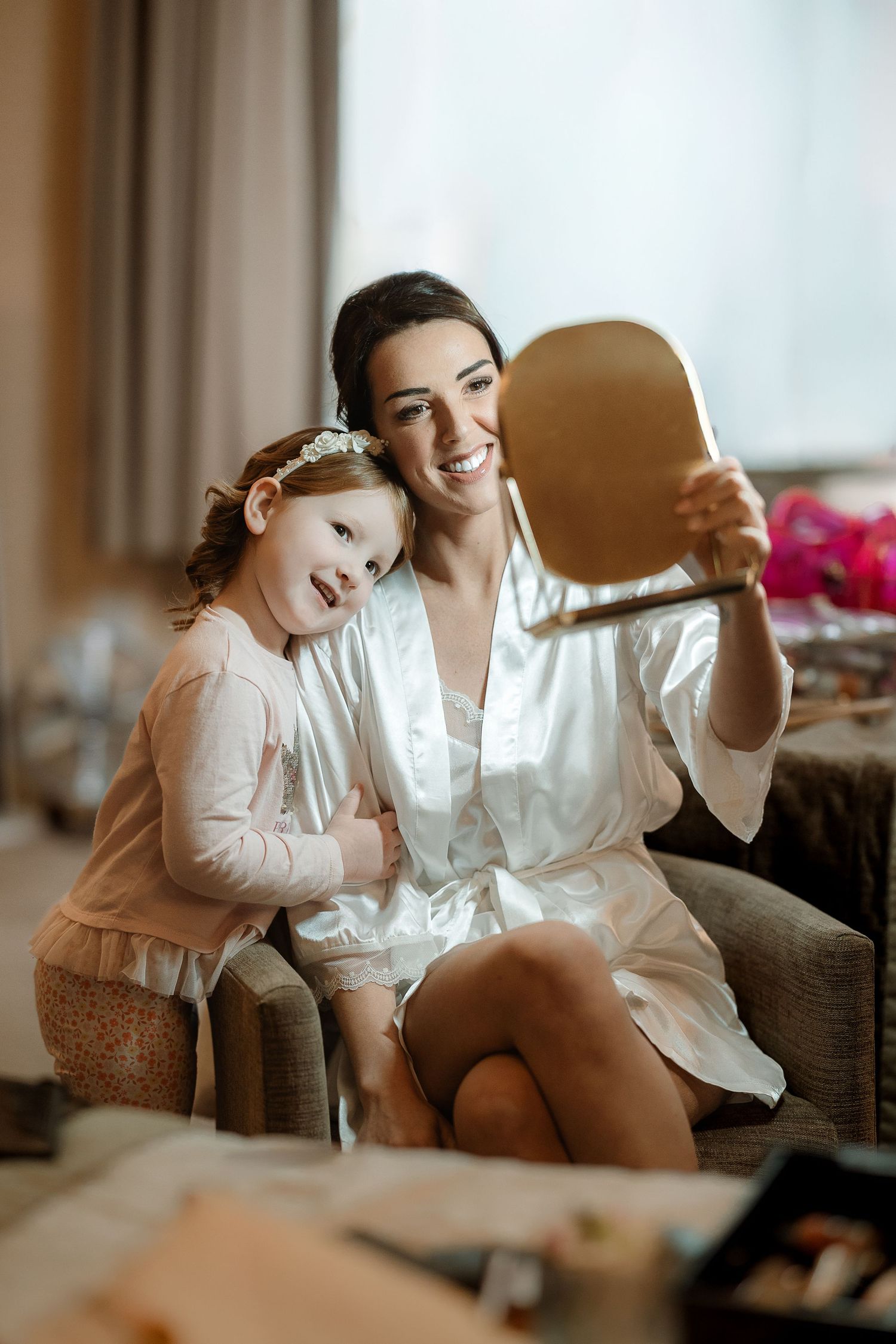 Two people share a joyful moment while sitting together on a couch in warm indoor lighting.