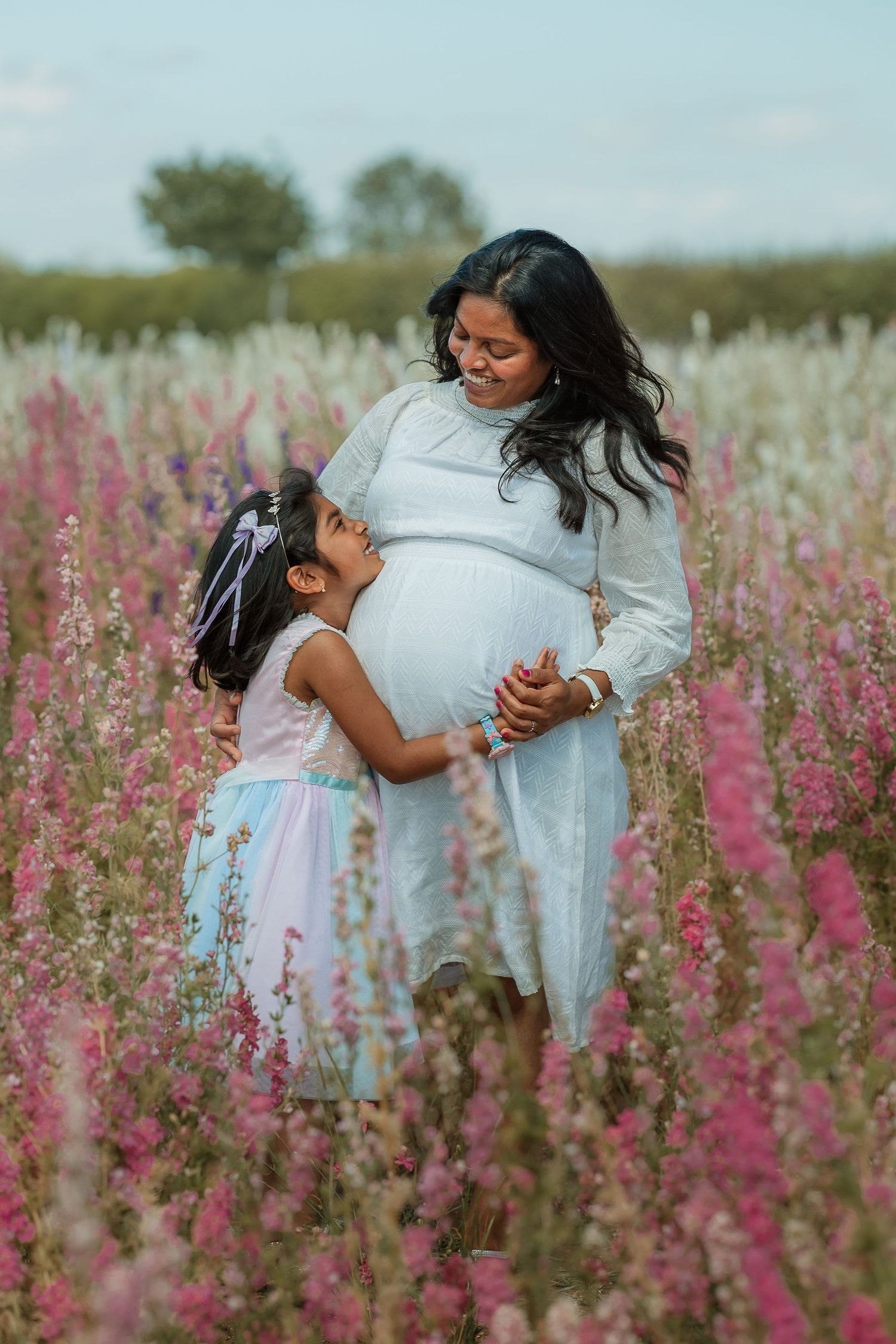 Two people share a tender moment while dancing together in a field of pink wildflowers on a sunny day.