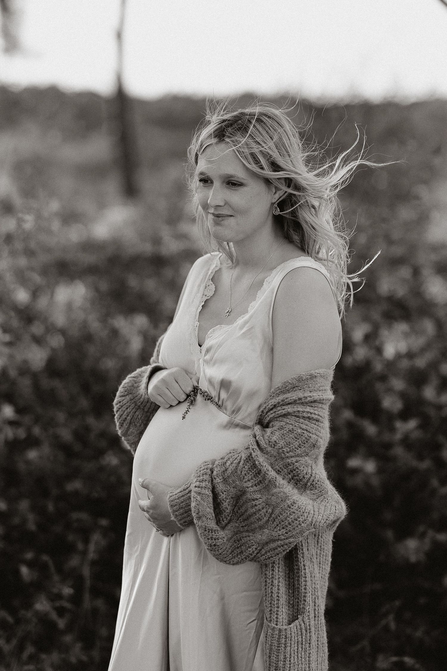 A series of black and white photos showing a person in a flowing white dress and gray sweater with wind-blown hair.