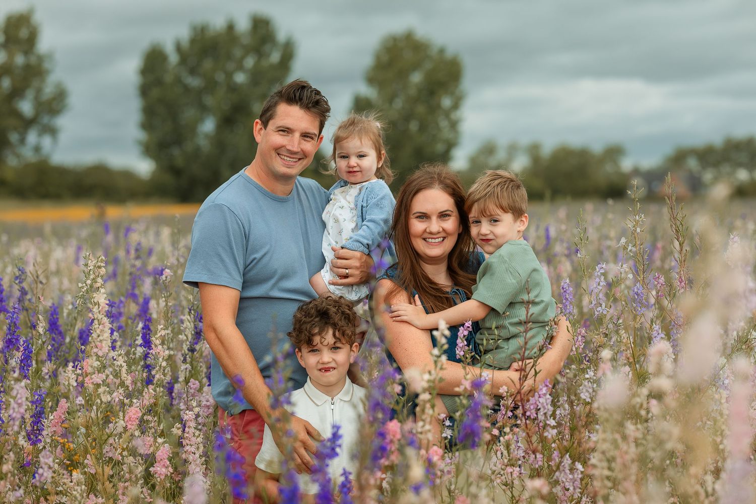Family enjoying a summer day together in a vibrant purple wildflower field during golden hour.