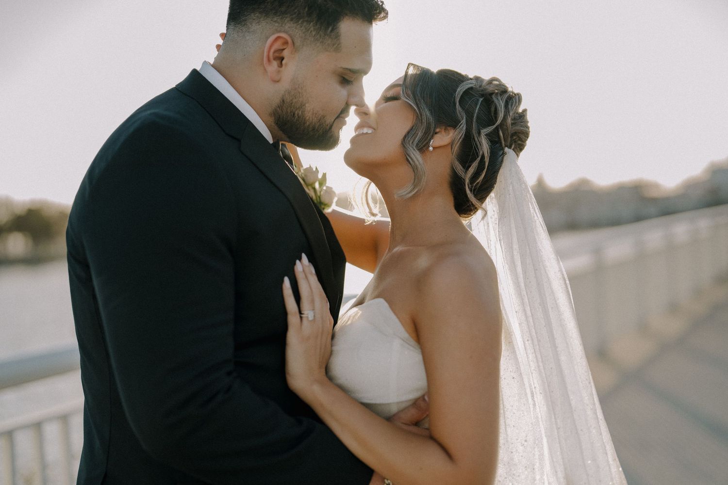 Bride and groom share an intimate moment on a bridge at golden hour during their wedding.