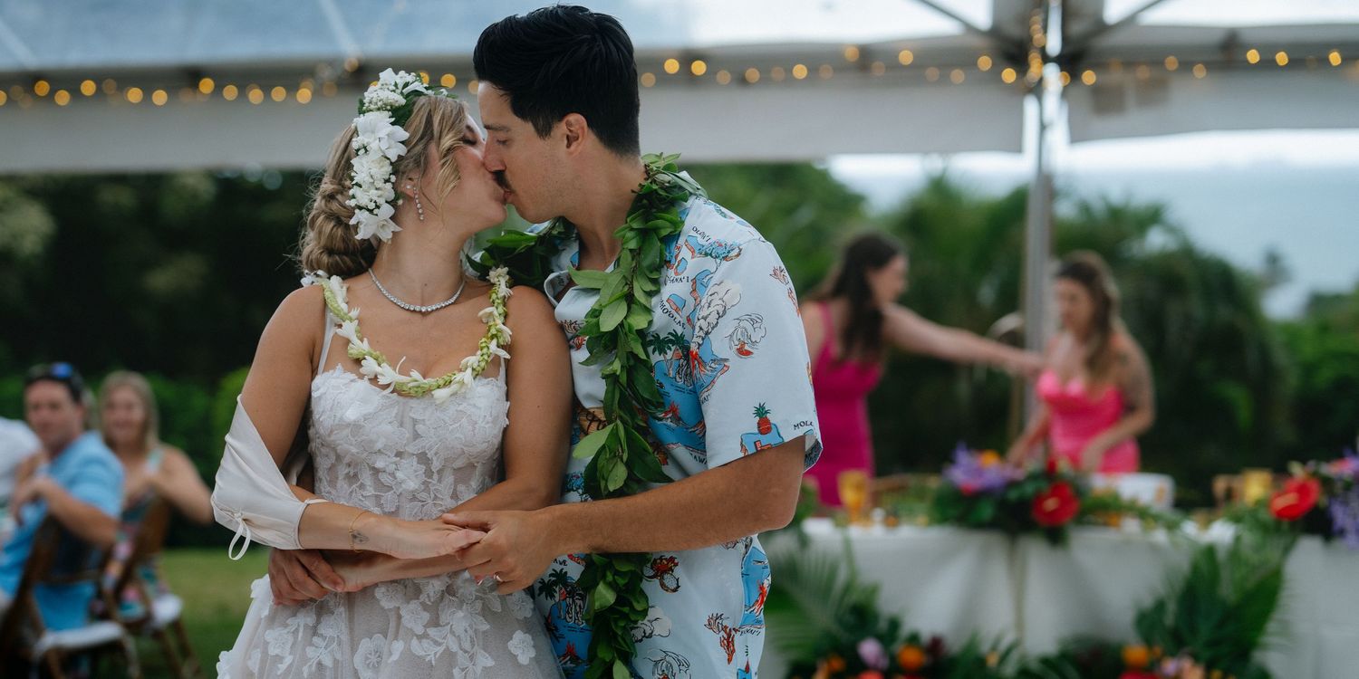 Bride and groom sharing their first dance under a tent at a lush tropical outdoor wedding celebration.