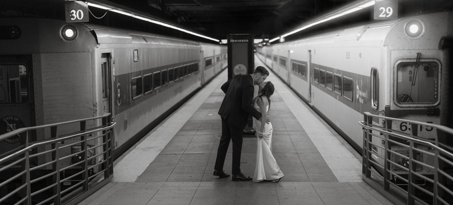 Black and white photo of bride and groom sharing an intimate moment on a Grand Central Terminal train platform.